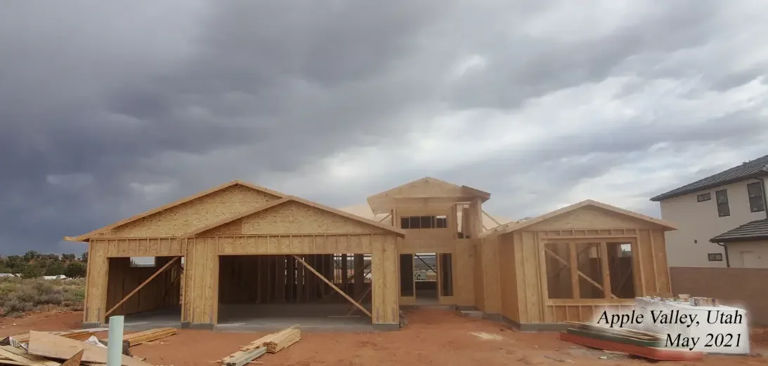 A house under construction with wooden framing in Apple Valley, Utah, May 2021, under a cloudy sky.