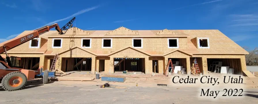 Construction site of a multi-unit residential building in Cedar City, Utah, in May 2022, with a crane and unfinished brickwork.