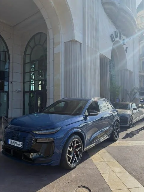 Une voiture bleue moderne garée devant un bâtiment avec des colonnes et de grandes fenêtres