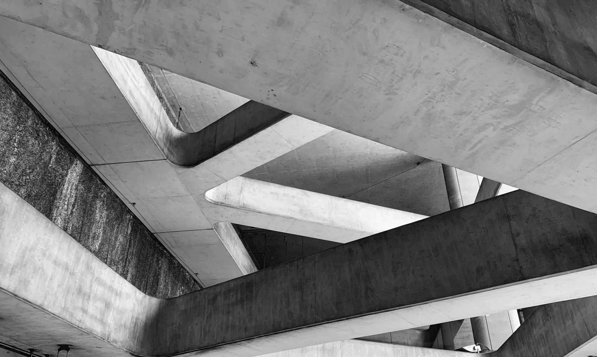 Estructuras de concreto en un edificio moderno, con líneas curvas y detalles arquitectónicos en diferentes niveles.