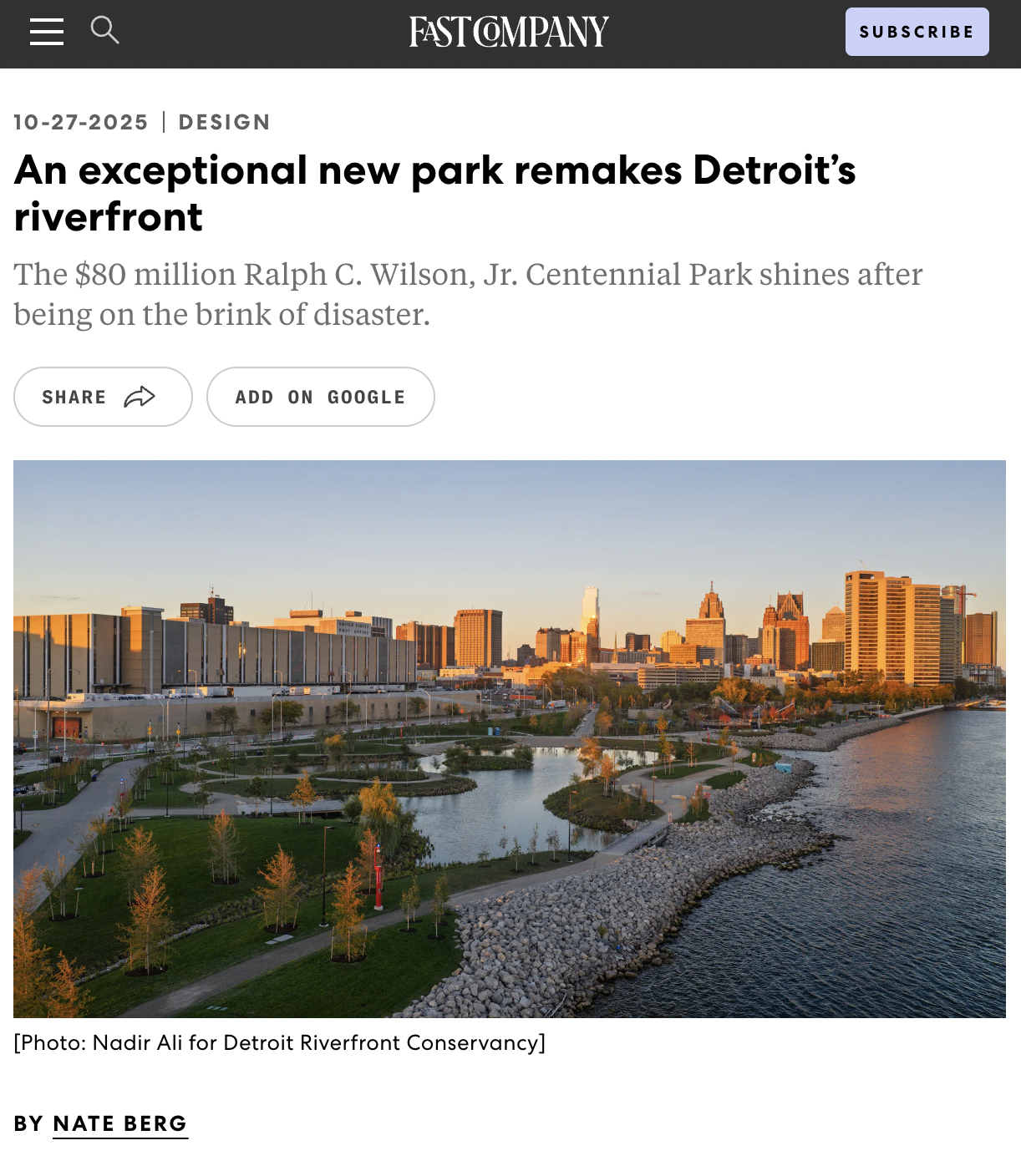 City skyline of Detroit with modern buildings, park with walking paths, trees, and a riverfront during sunset.