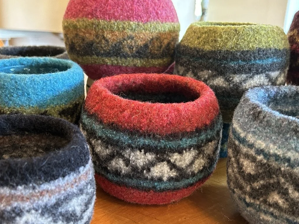 Colorful felted wool bowls with intricate patterns arranged on a wooden surface.