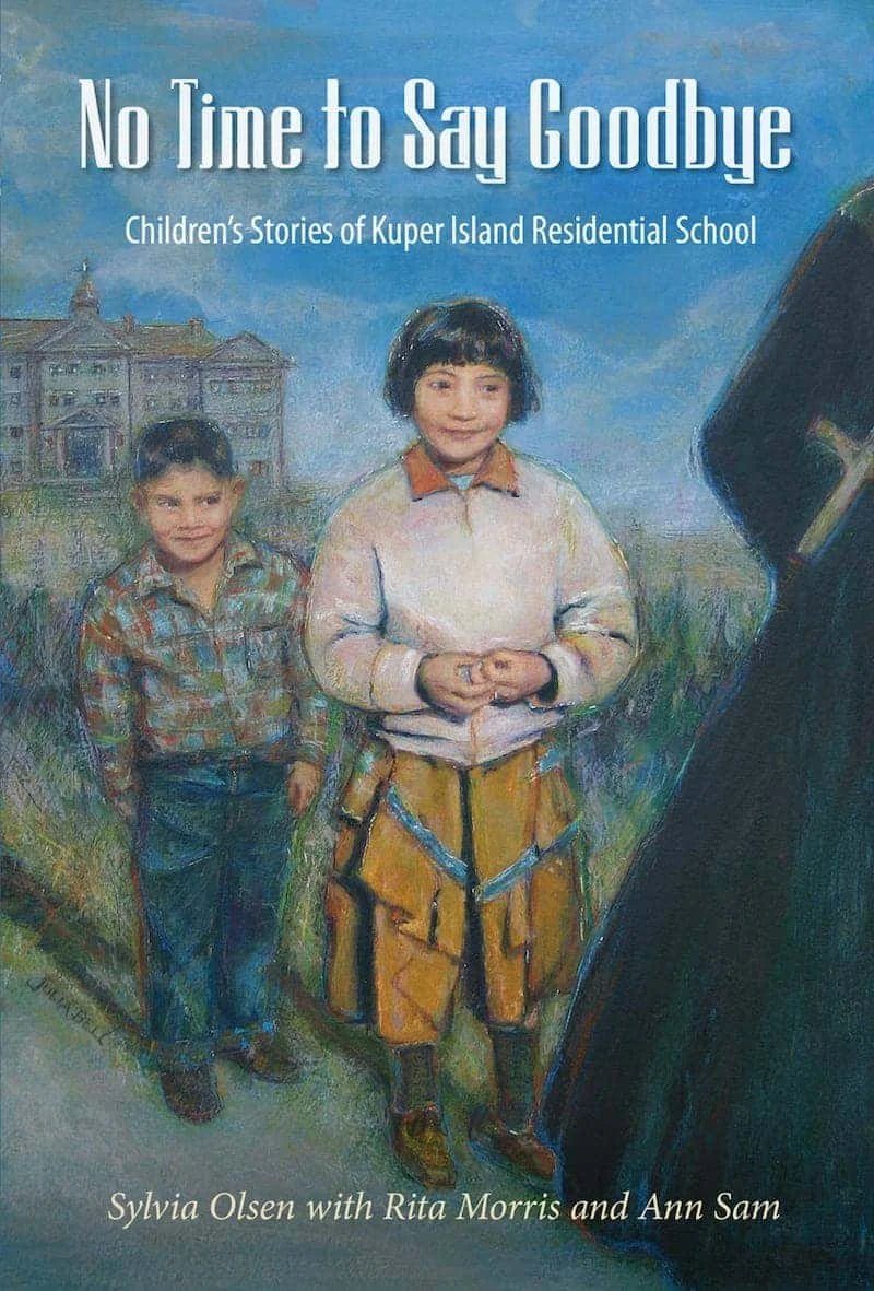 An illustrated book cover titled 'No Time to Say Goodbye: Children's Stories of Kuper Island Residential School' by Sylvia Olsen with Rita Morris and Ann Sam. It depicts two children, a boy and a girl, standing outdoors in front of a large building. The girl has short dark hair, wearing a light-colored jacket and yellow pants with dark patches, and the boy has short dark hair, wearing a colorful plaid shirt and jeans.