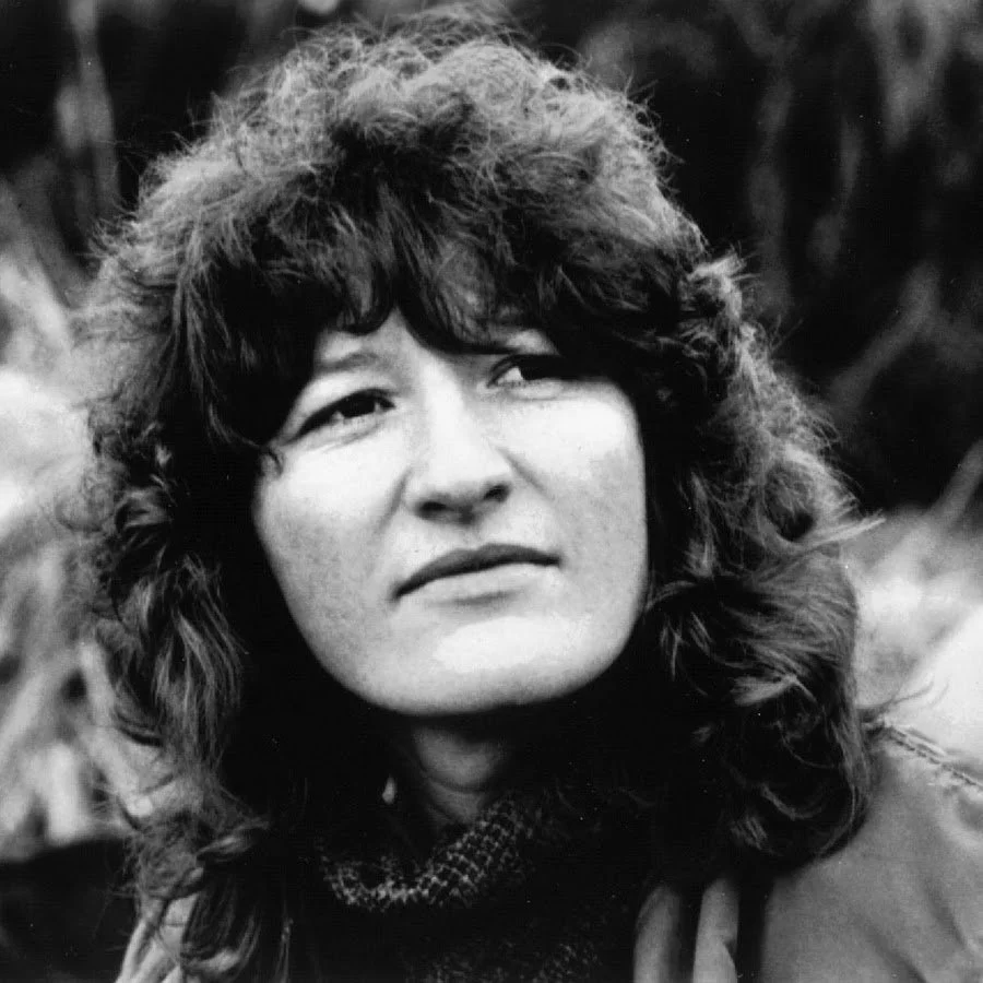Black and white photo of a woman with curly hair, looking to the side.