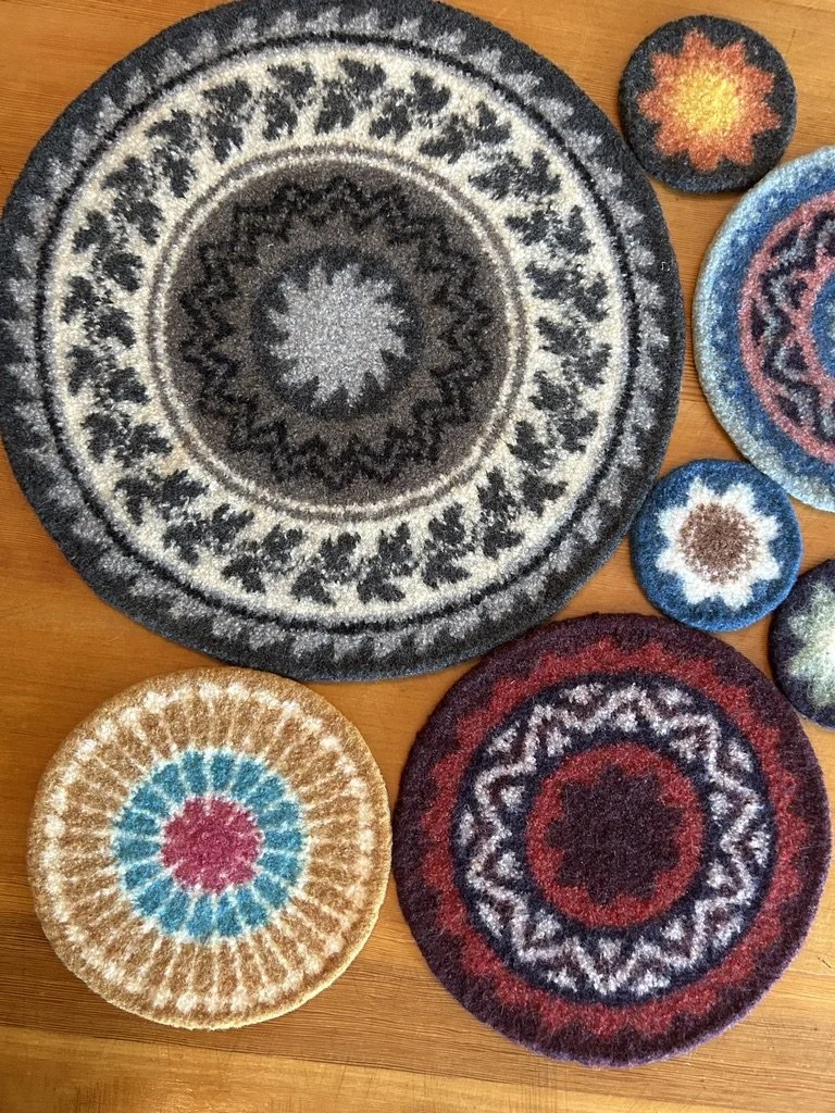 A collection of colorful, patterned felted coasters on a wooden surface, featuring various circular designs.