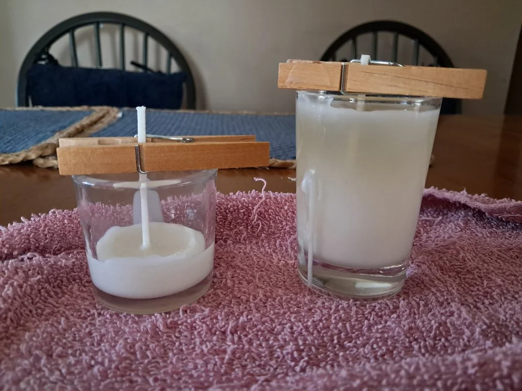 Two glass votive candle holders, one full and the other partially full, sit on a kitchen table