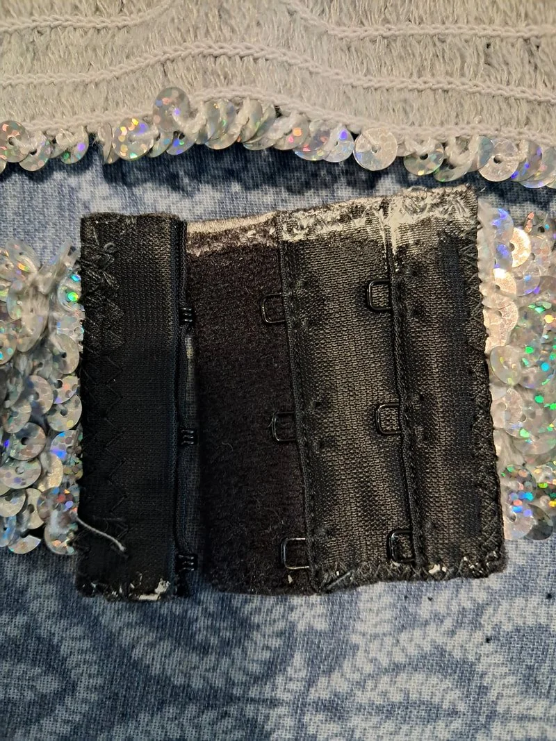 Black bra hook and eye clasp with white glue residue on the top edge
