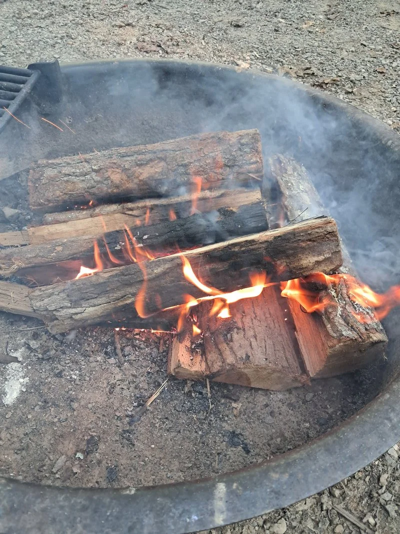 A small fire burns in a metal fire ring