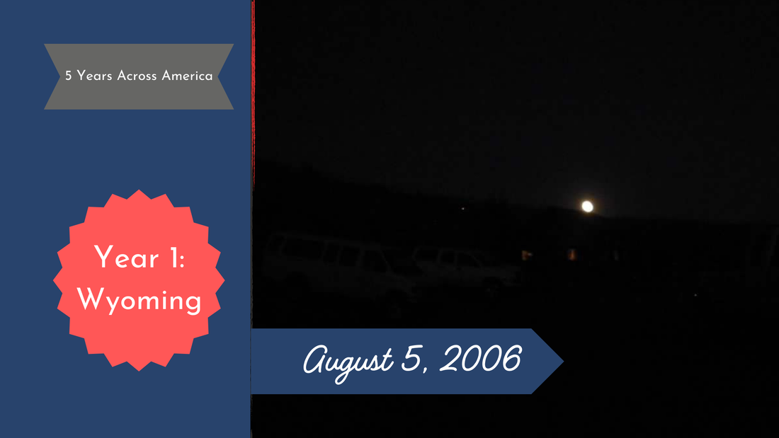 Pale yellow full moon cresing over a hill