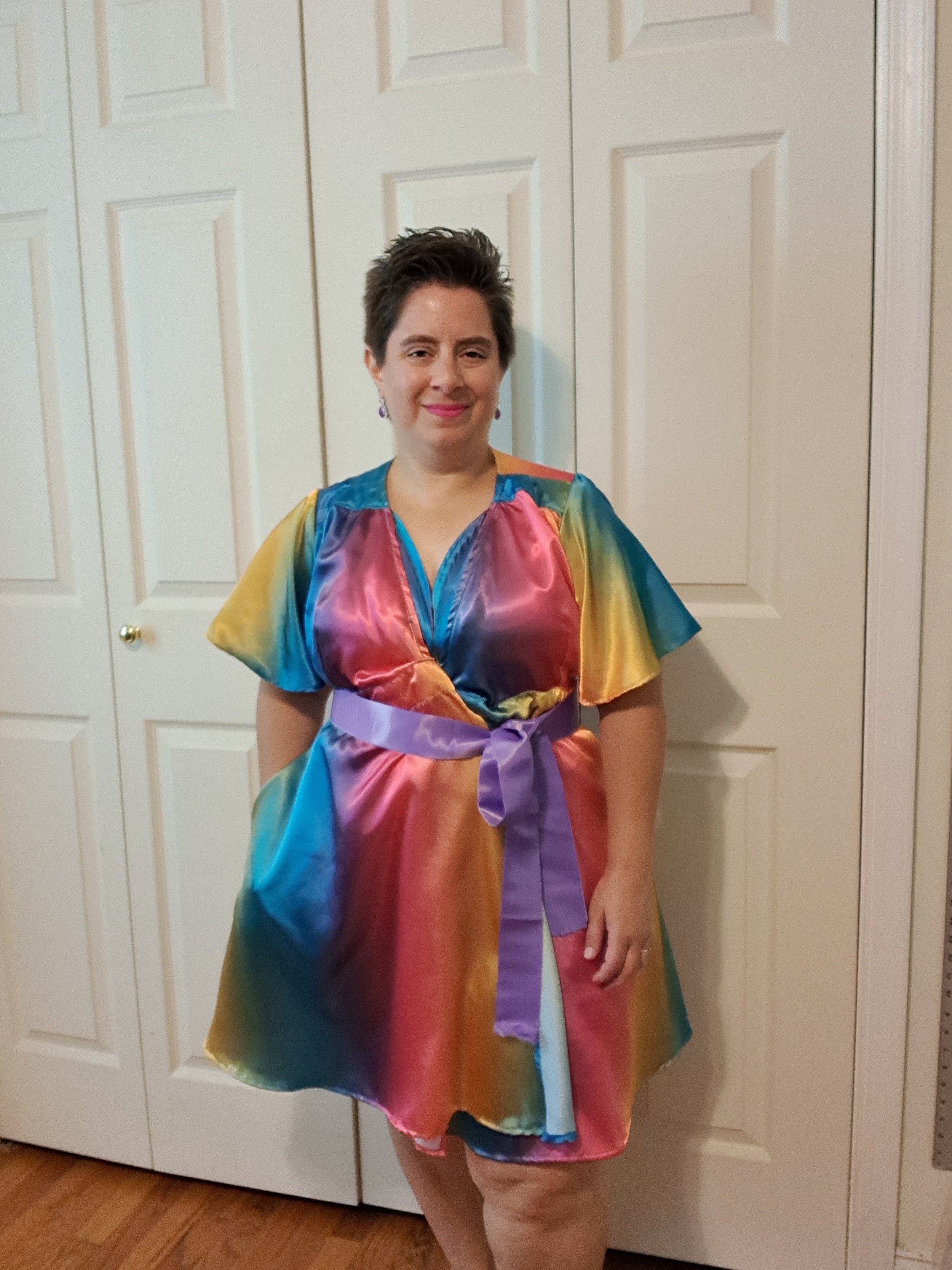 Smiling white woman with short brown hair wears a satin ombre robe with a contrast sash