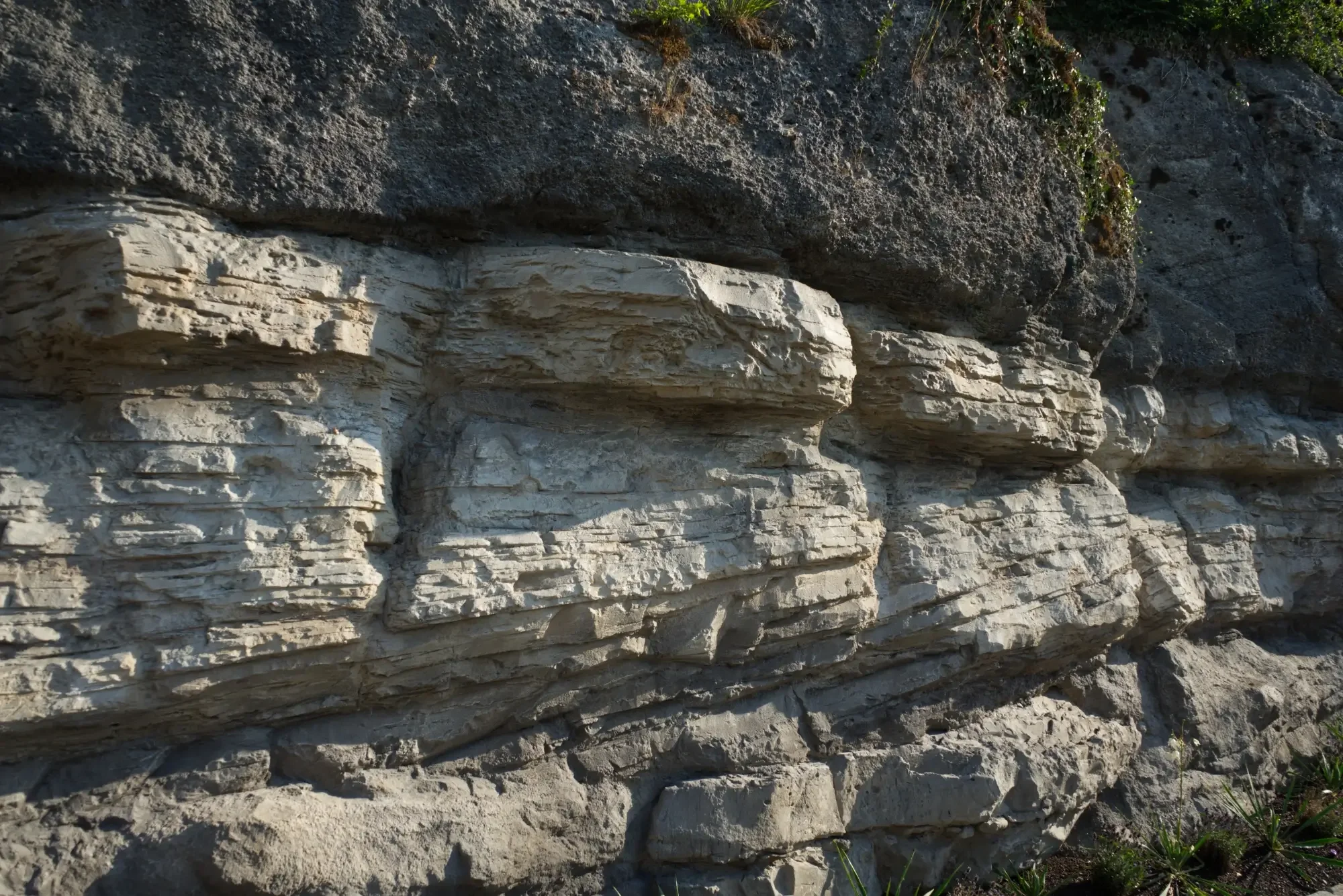 Detail einer Felswand mit horizontalen Schichten und tiefen Fugen