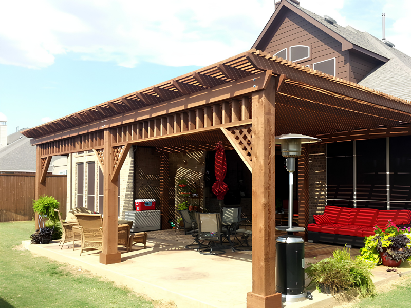 Backyard patio with wooden pergola, patio furniture including a red outdoor sofa, a heater, and potted plants.