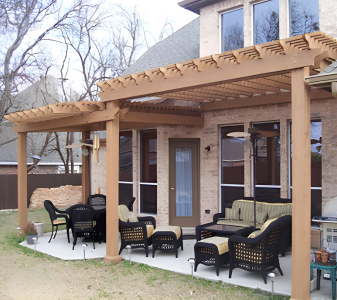 Backyard patio with wooden pergola, outdoor seating including sofas and chairs, and a small table.