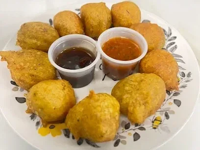 Plate of fried food balls with two dipping sauces, one dark and one orange.