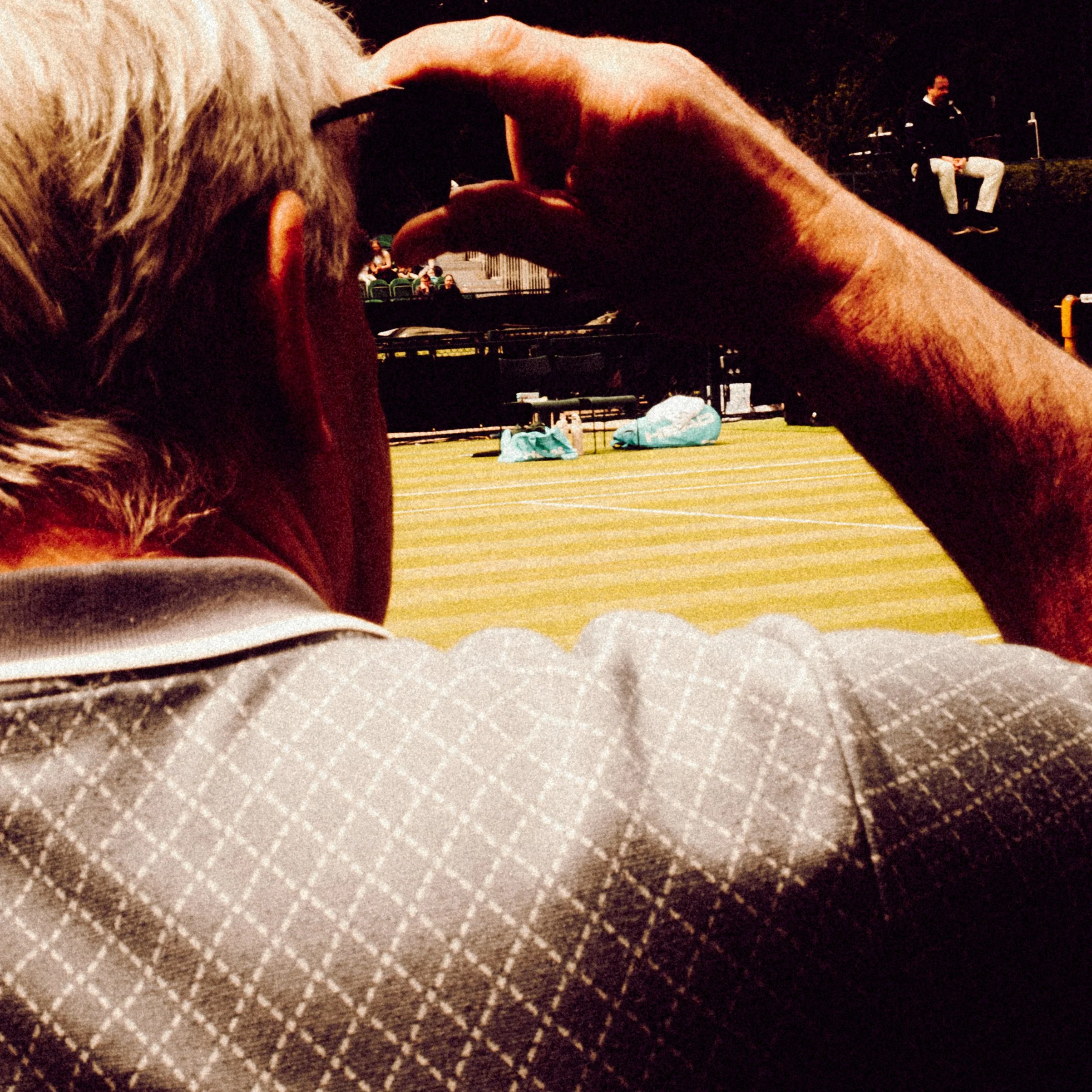 A person watching a game of tennis, umpire visible in the background.