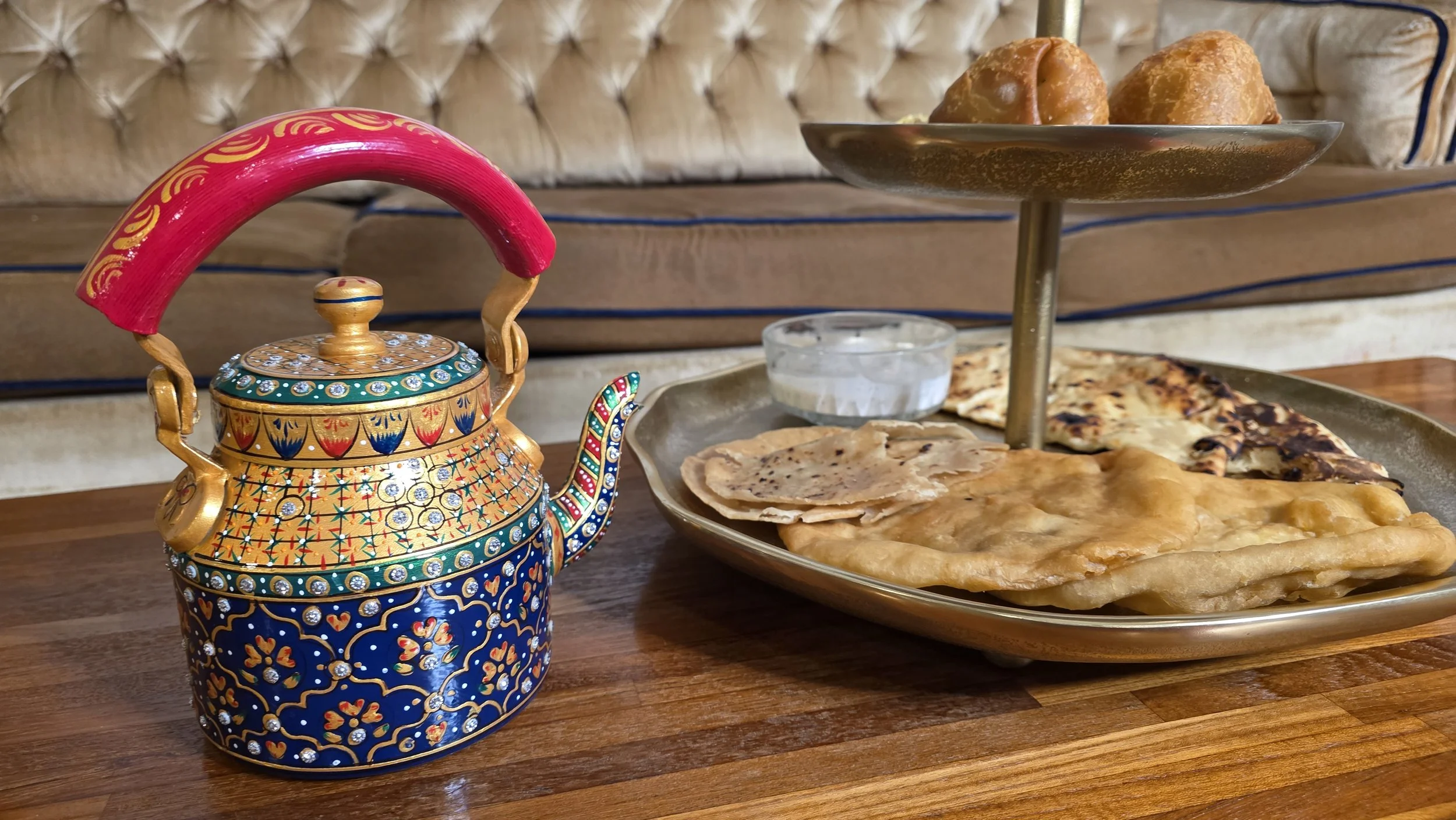 Luxe Tea product photo depicting ornate hand painted teapot and tea tower filled with roti, naan, and samosas