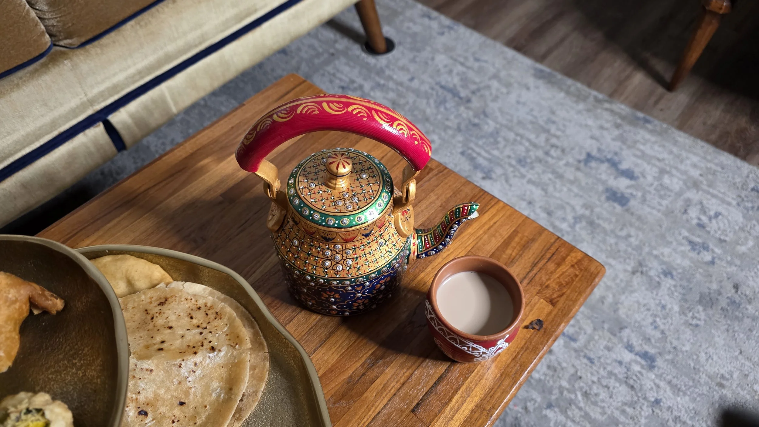 Luxe Tea overhead product photo depicting teapot, cup of chai, and a tea tower of Indian food