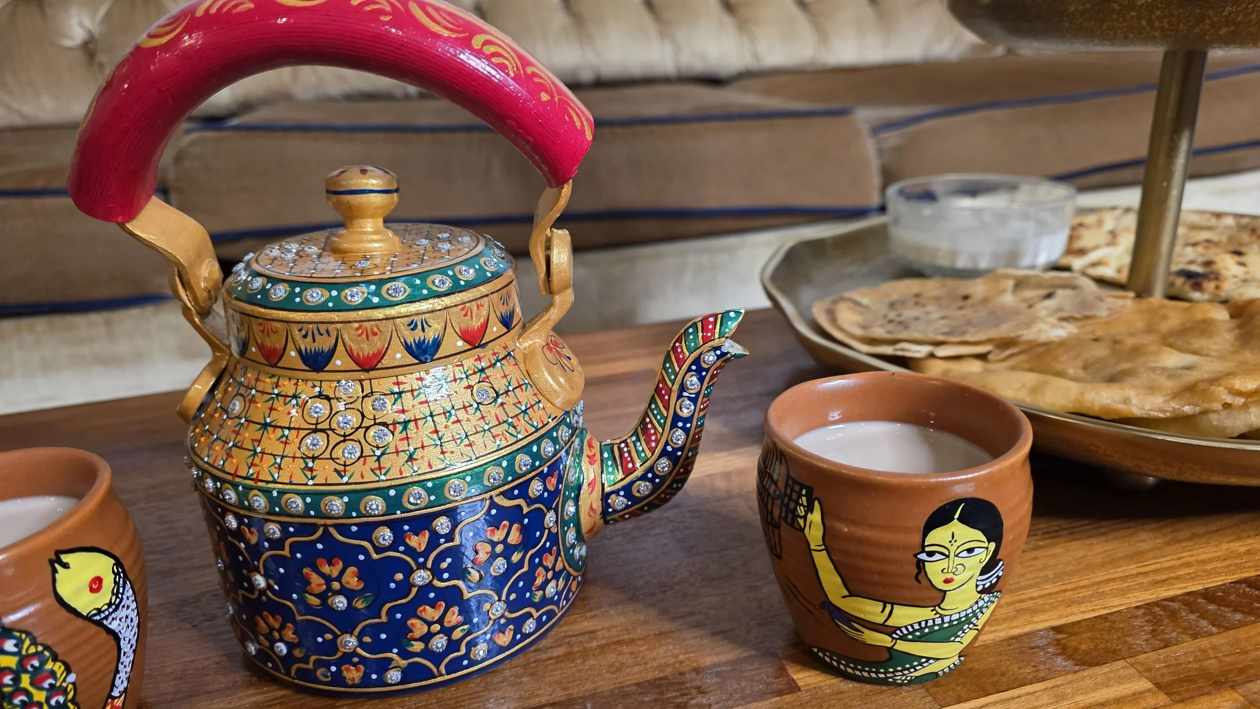 Luxe Tea product photo depicting ornate hand painted teapot and clay cup filled with masala chai