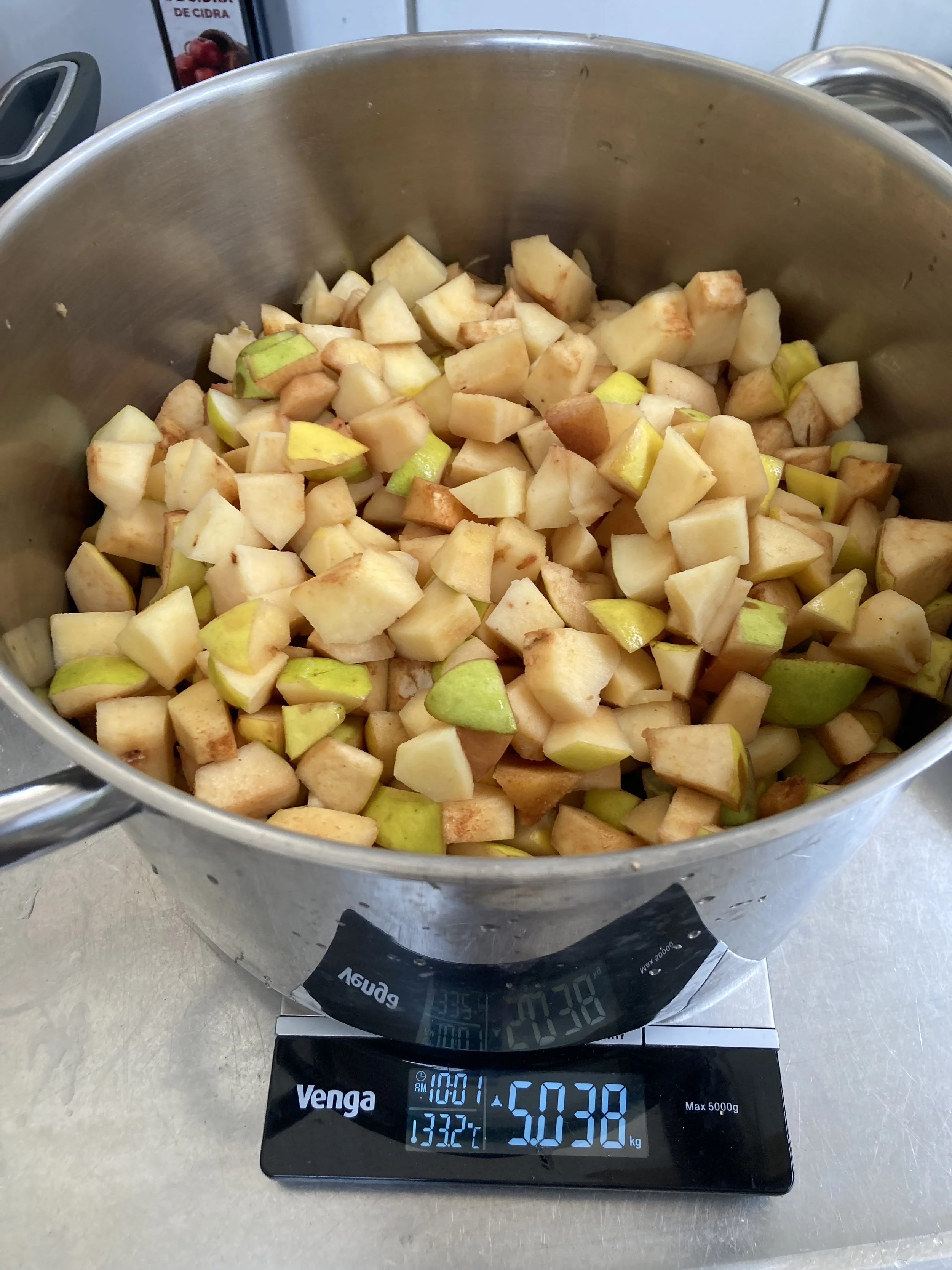 A digital kitchen scale showing the weight of chopped pears as 5.038 kilograms.