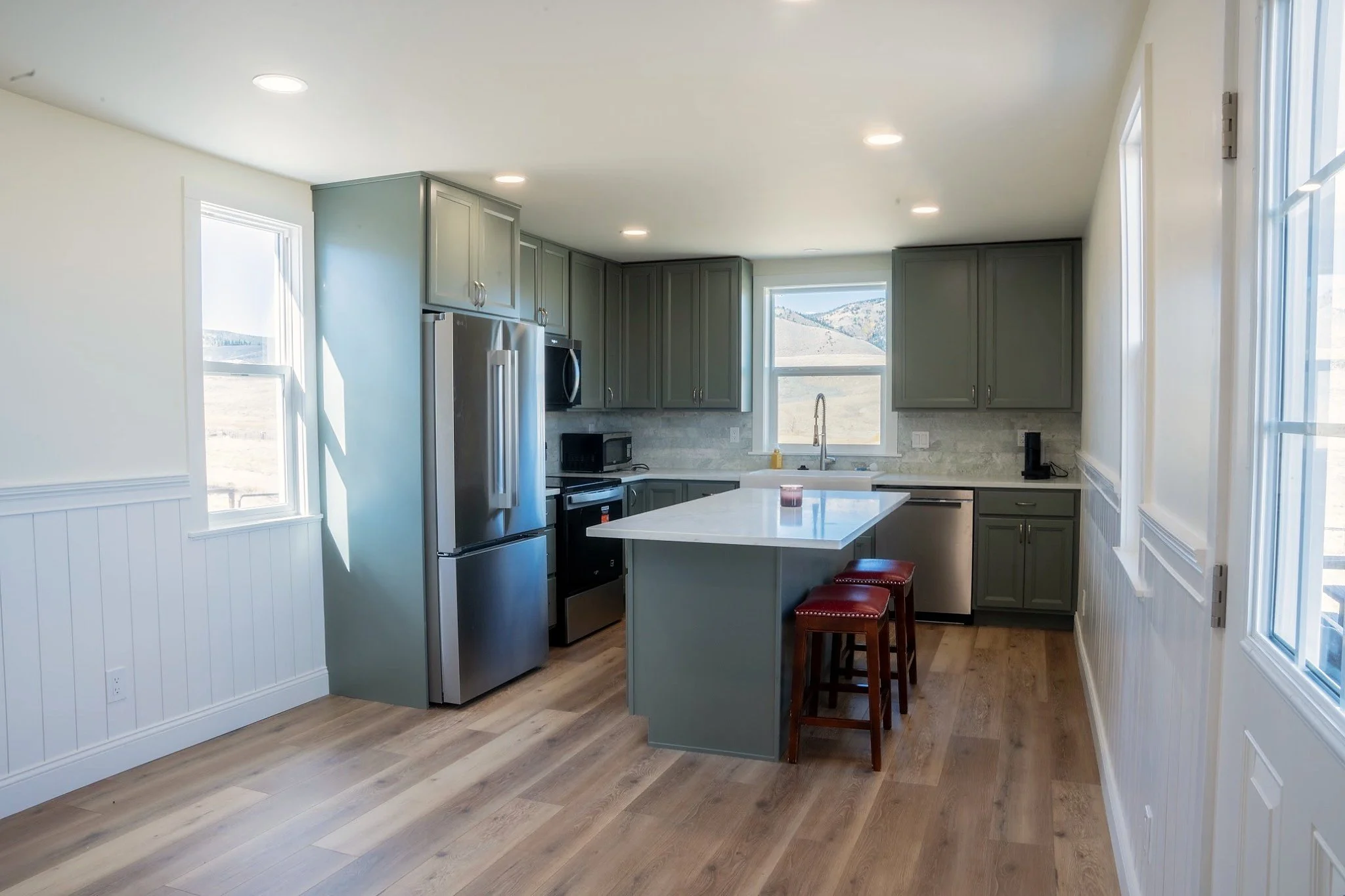 Relocated kitchen with custom cabinetry, island, new countertops, backsplash, and appliances in Centennial, Wyoming.