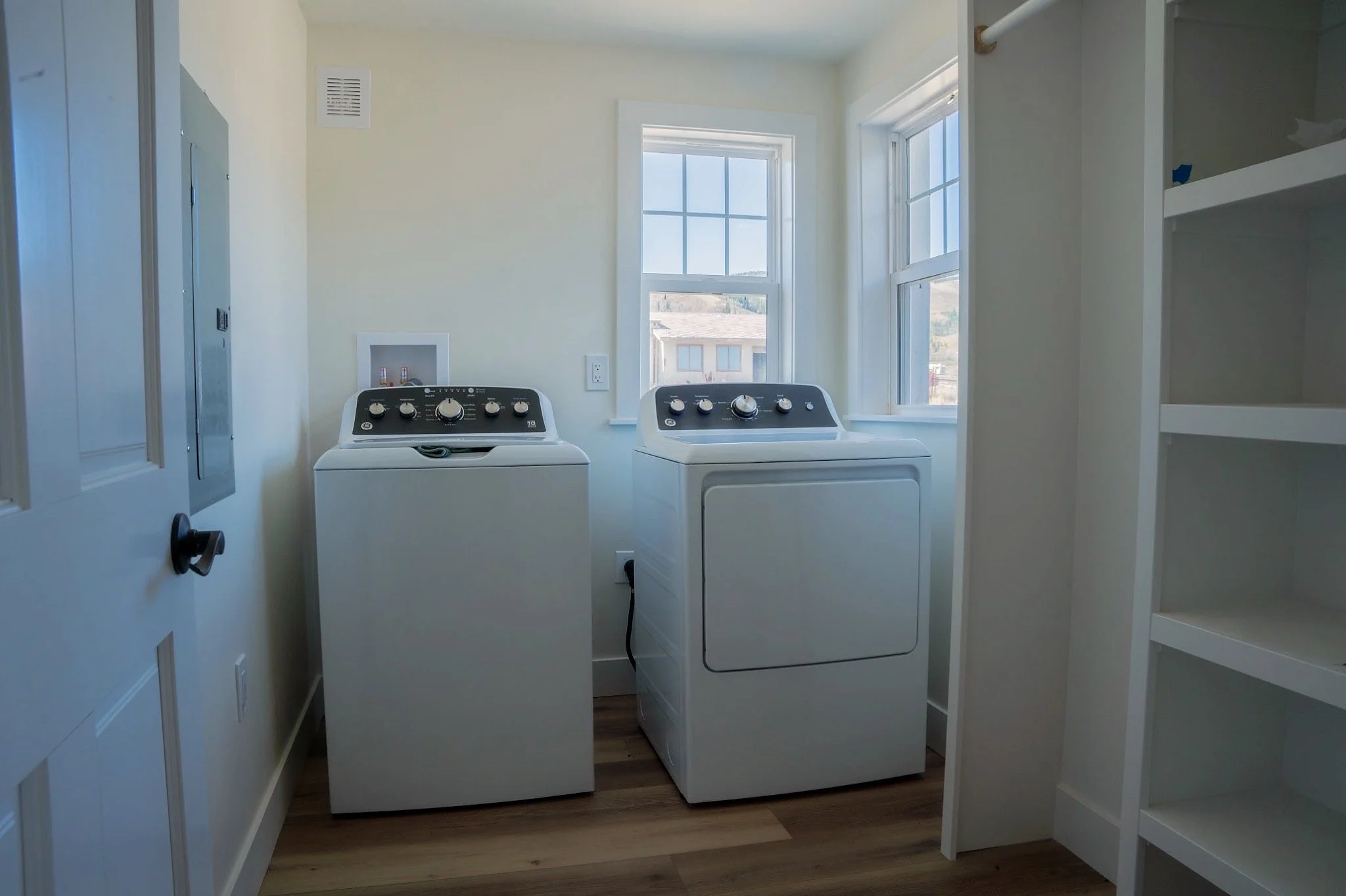 New utility room with washer and dryer, custom shelving, updated windows, flooring, and trim.