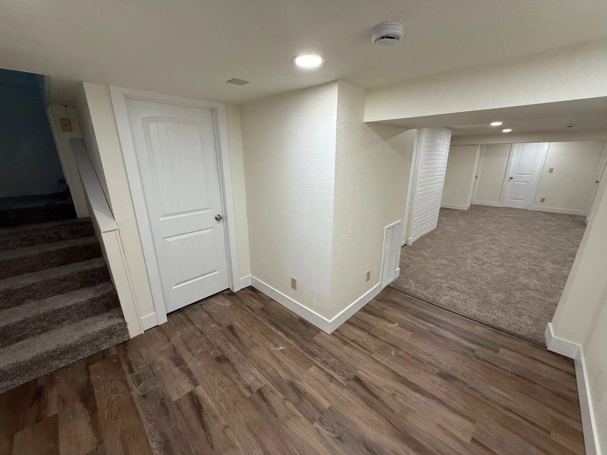 Completed basement reconstruction with new flooring, doors, trim, drywall, paint, and recessed lighting.