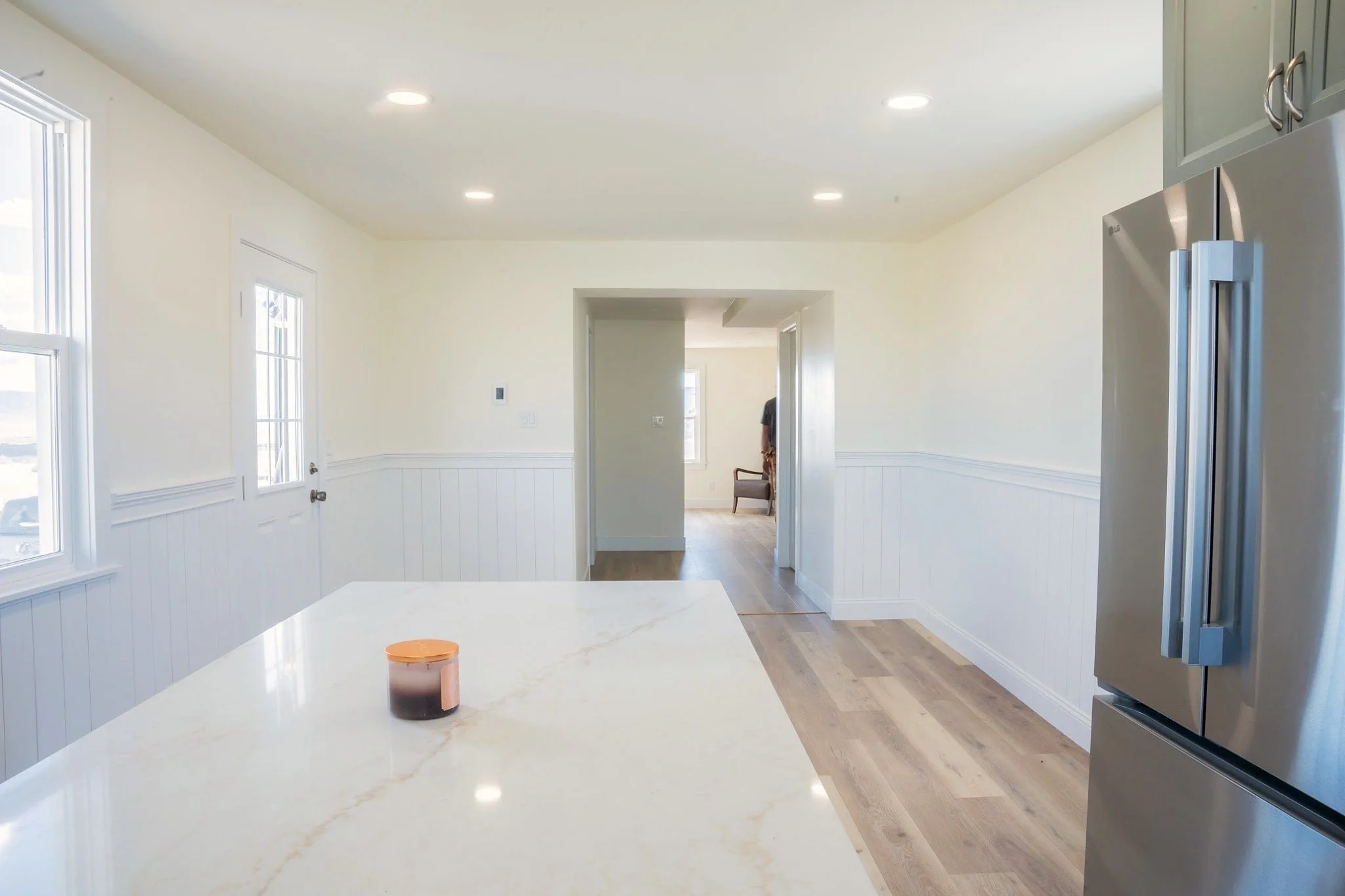 Kitchen island countertop and updated interior with new flooring, wall details, doors, and trim.