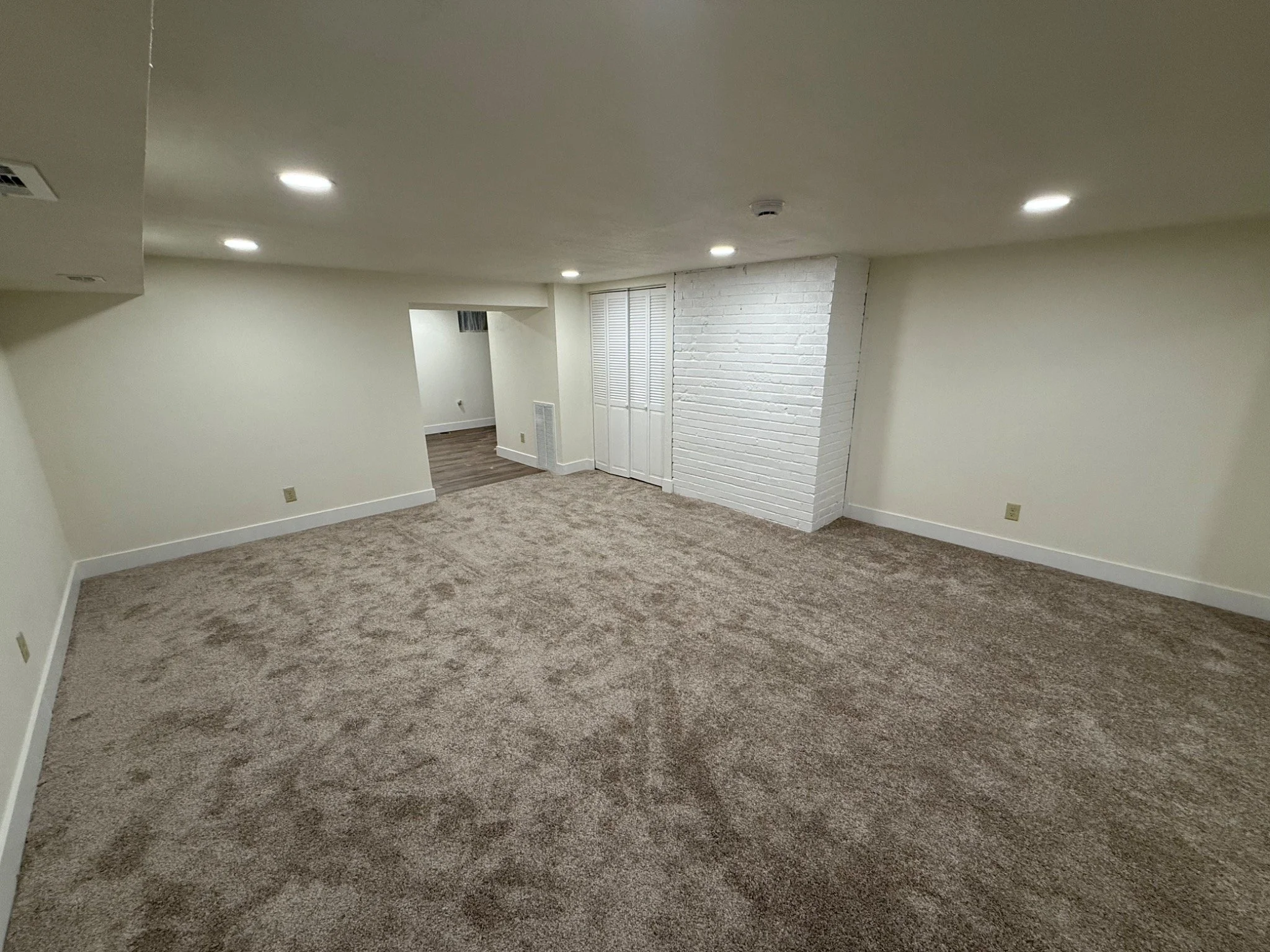 Rebuilt basement living area with new carpet, finished walls, doors, and trim.