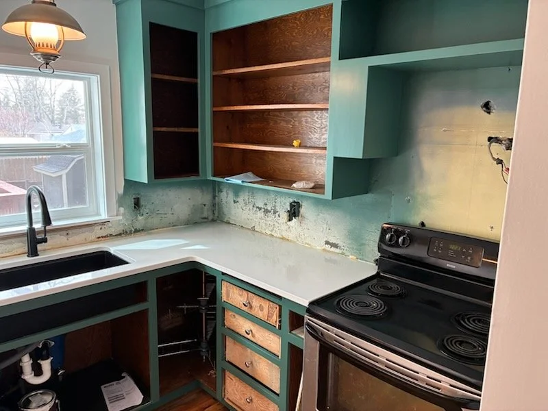 During: Refurbished cabinetry with new countertops, sink, faucet, and window before final doors and backsplash.