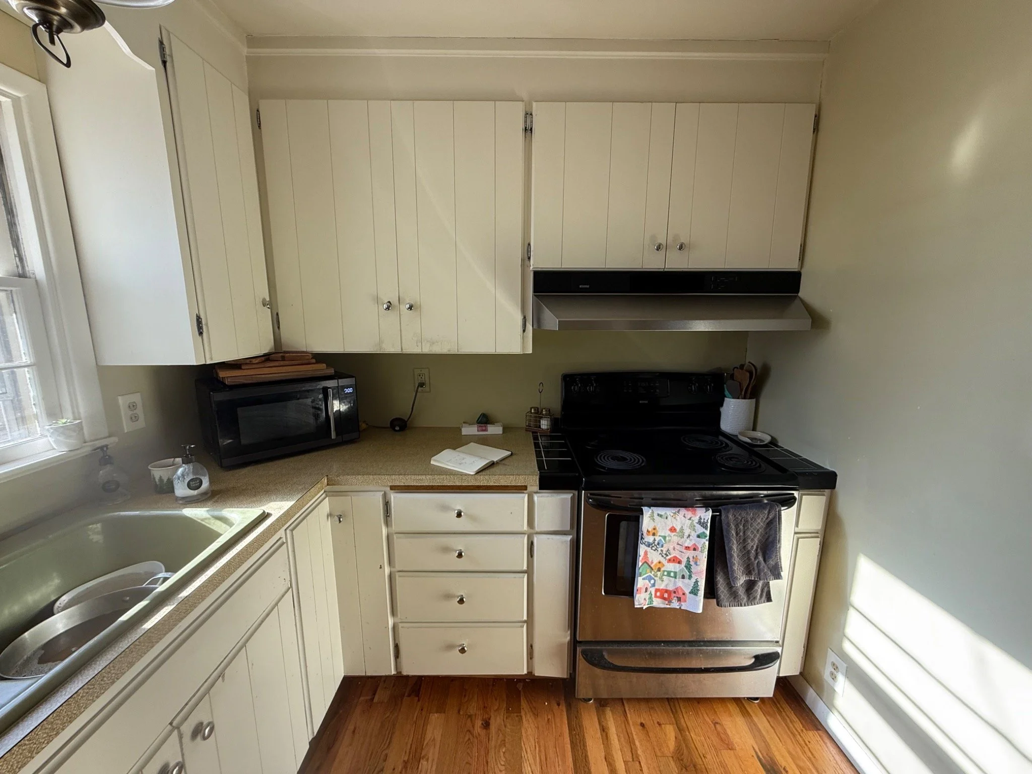 Before: The original kitchen with older cabinet doors, hardware, sink, countertops, and range hood.