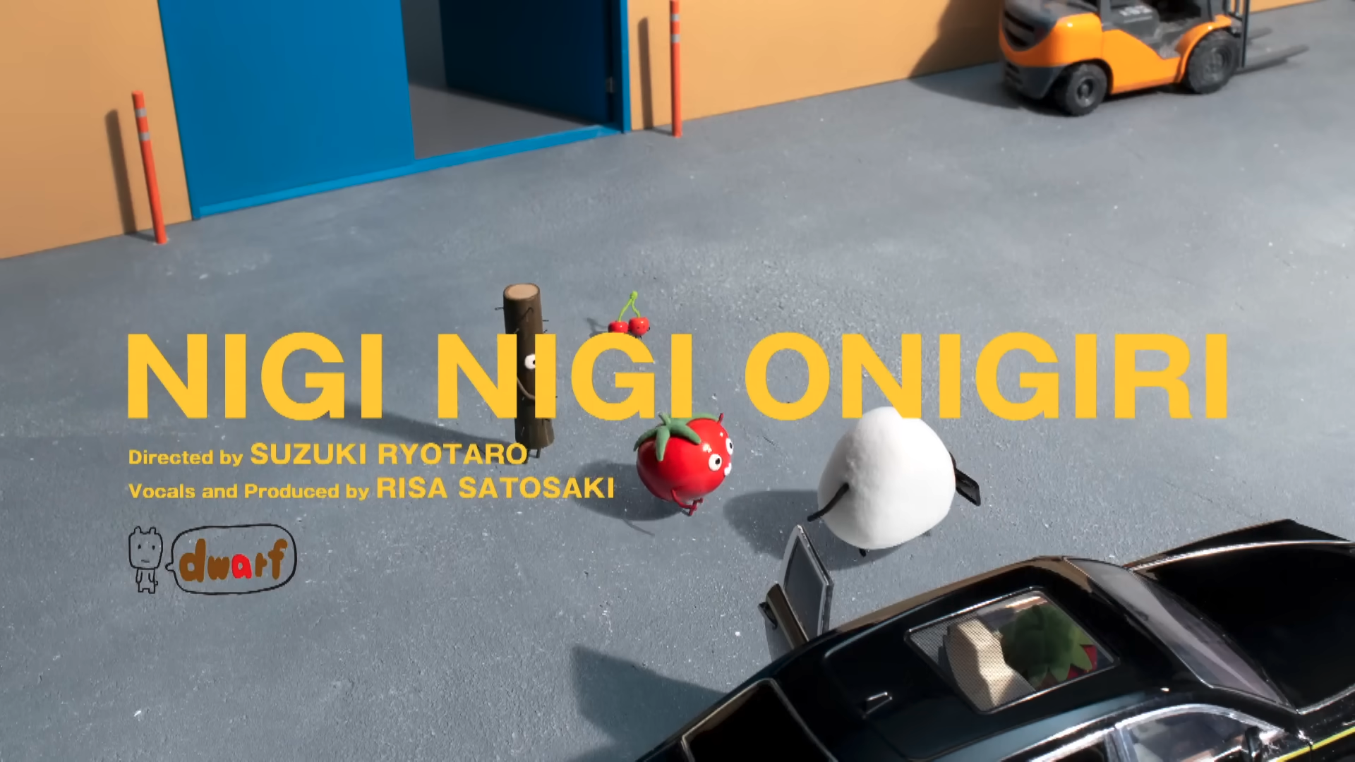Title screen of a children's animation show titled "NIGI NIGI ONIGIRI" directed by Suzuki Ryutaro and produced by Risa Satosaki, featuring cartoon characters including a tomato, onion, and other vegetables on a gray surface near a black toy car, with colorful building structures in the background.