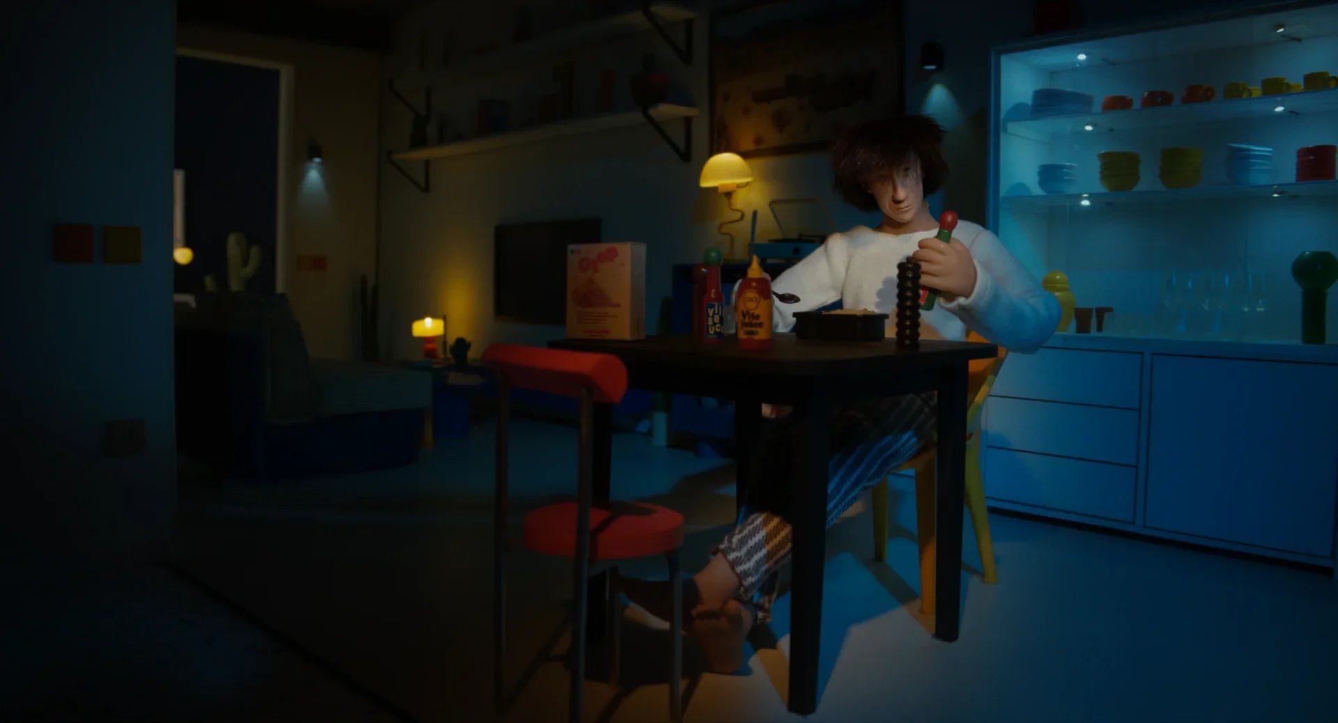 Child sitting at a dining table with condiment bottles, in a dimly lit room with colorful lighting, with kitchen cabinets and shelves in the background.