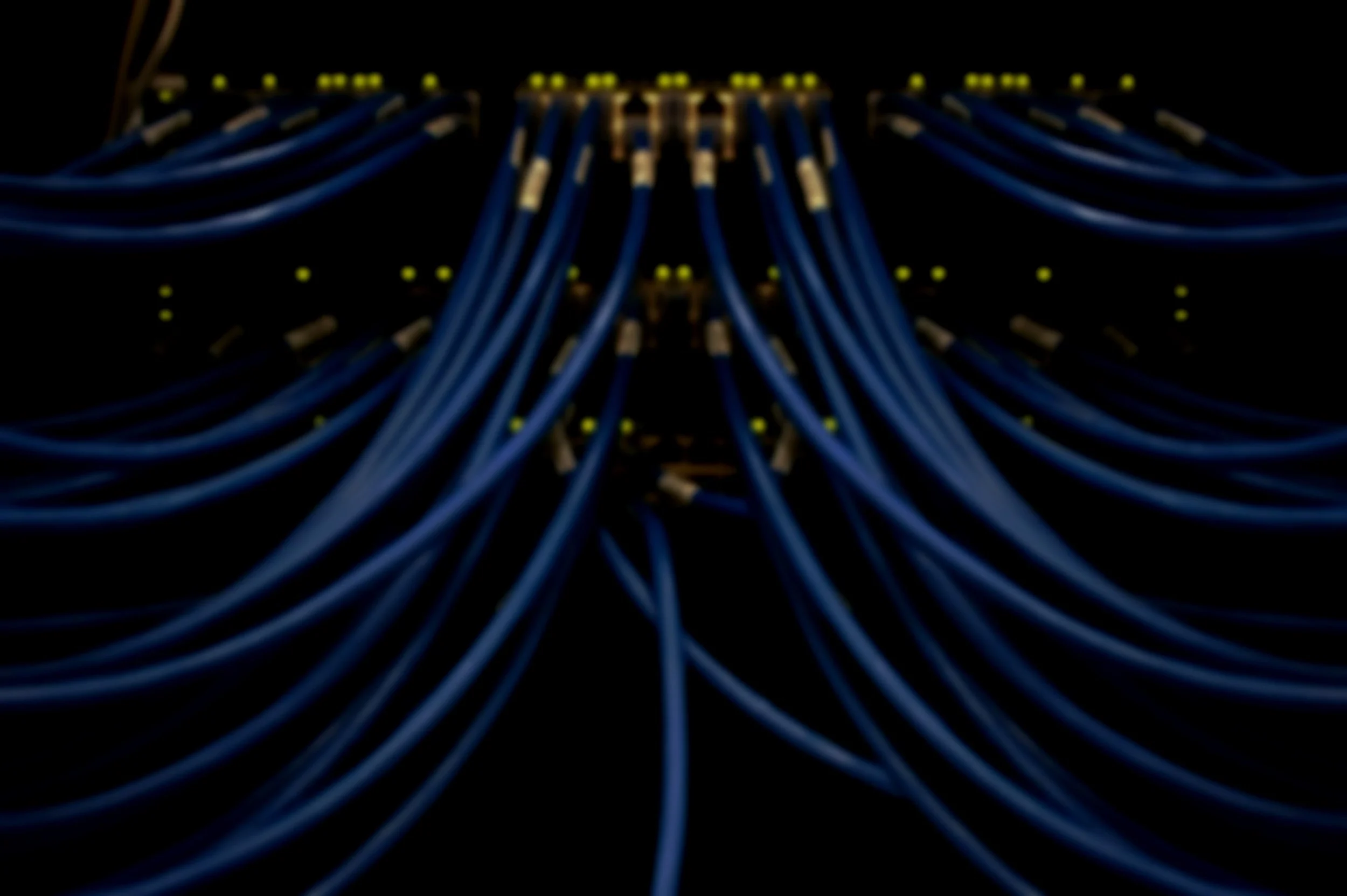 A close-up view of a network patch panel with multiple blue Ethernet cables connected to the ports, set against a black background.