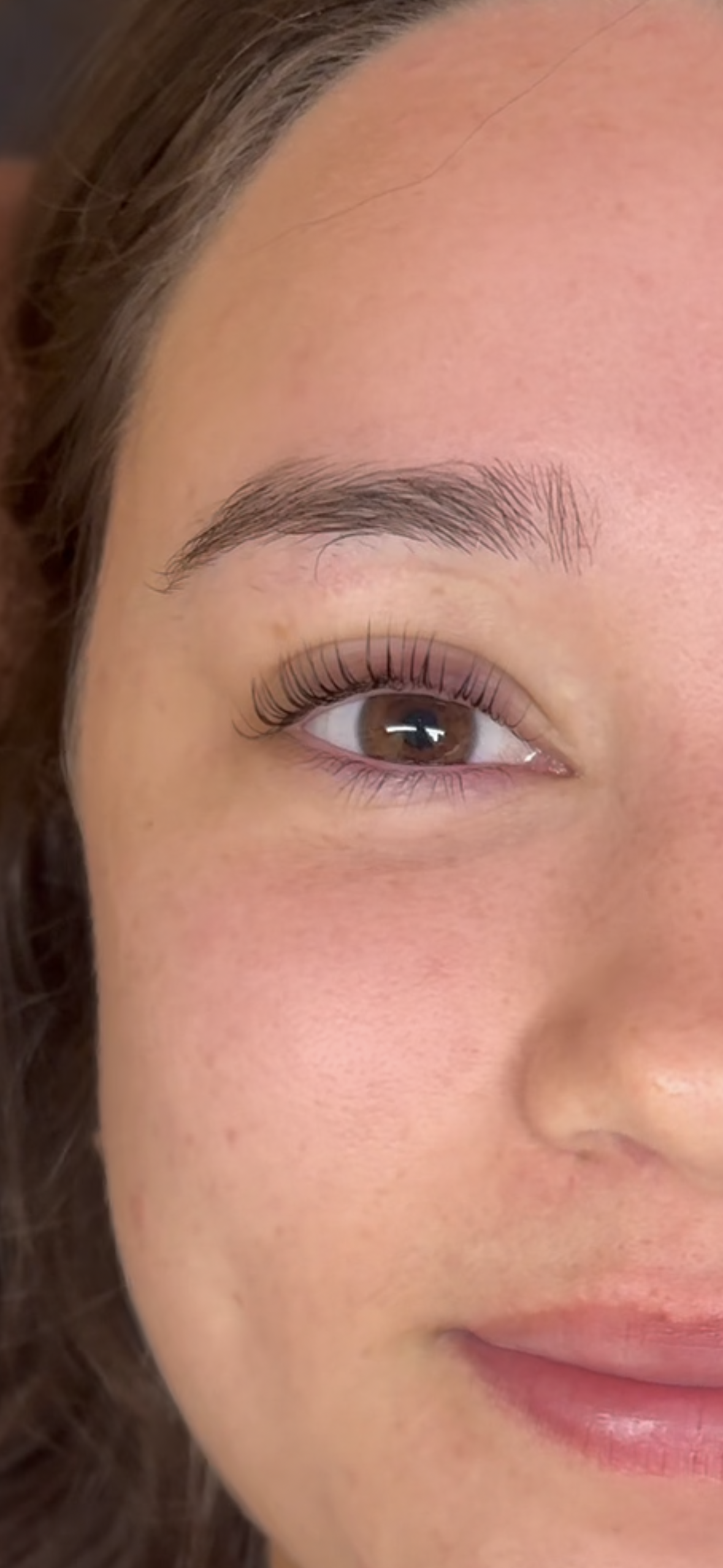 Close-up image of a woman's face showing her eye, eyebrow, and part of her cheek and lips.