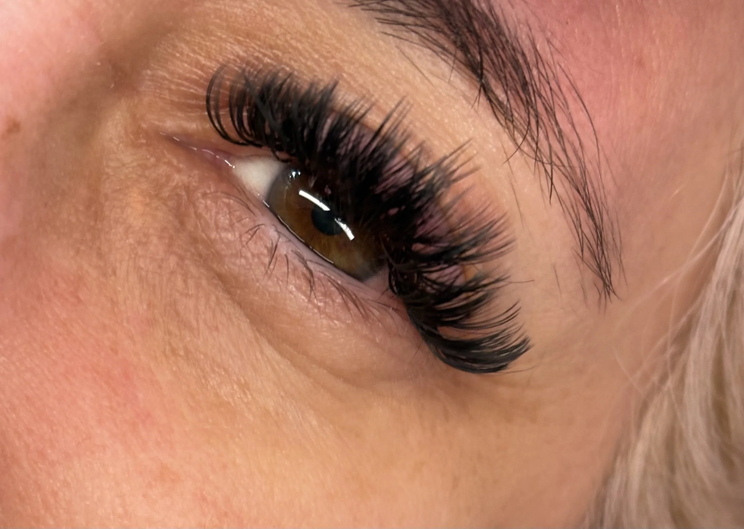 Close-up of a closed eye with long, dark eyelashes and well-defined eyebrow.