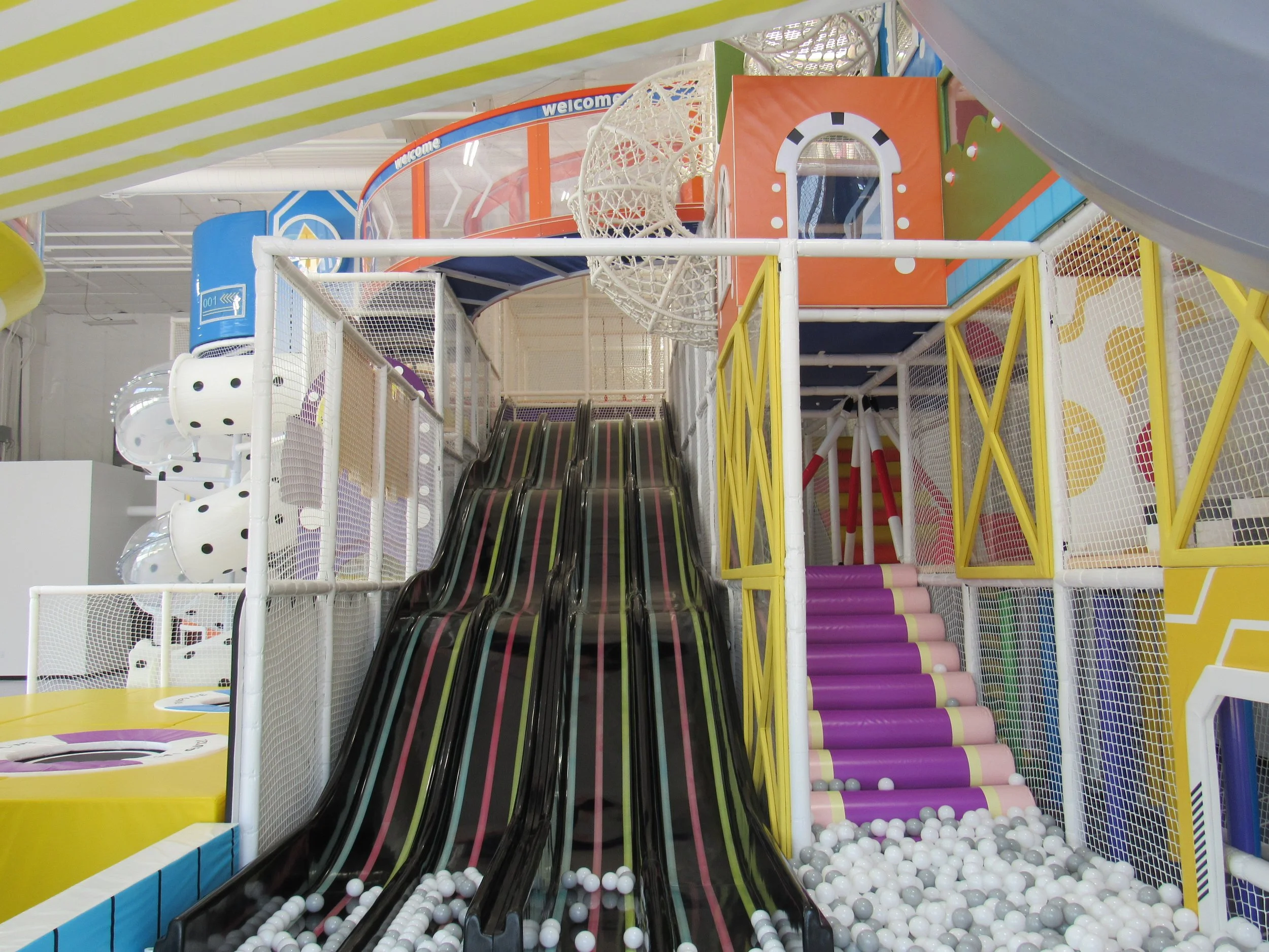 Indoor play area with multiple slides, ball pits, and colorful structures in a trampoline park.