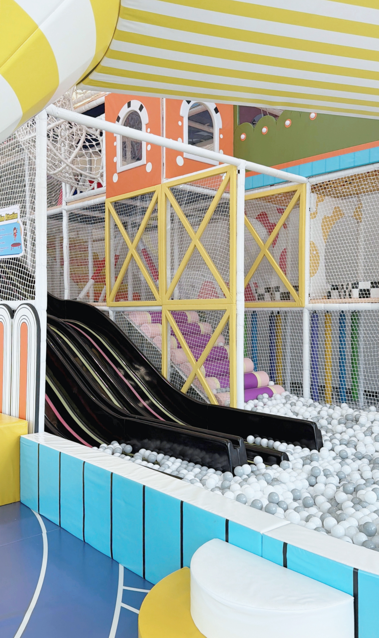 Colorful indoor children's playground with ball pit, slide, and climbing structures.