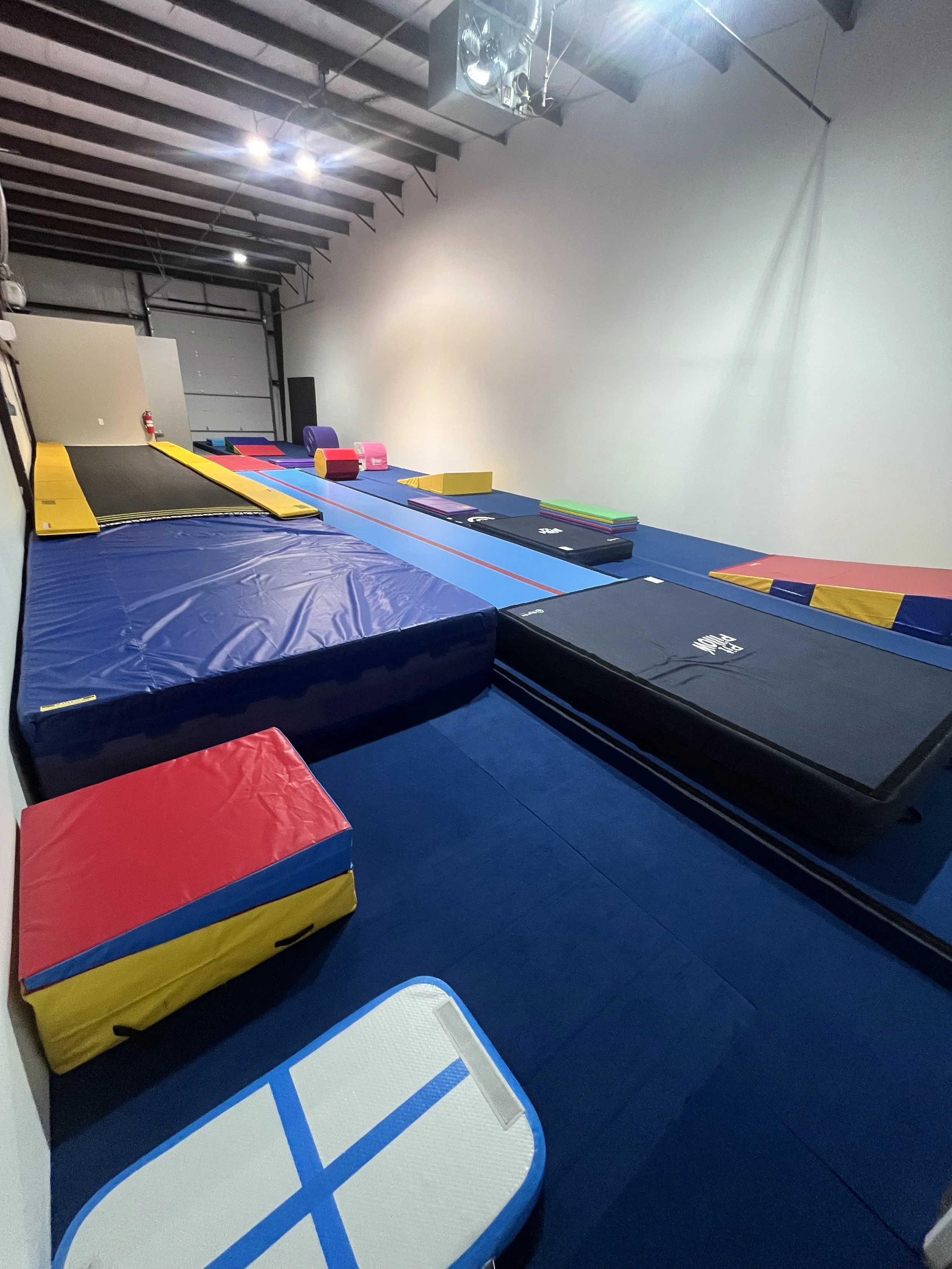Interior of the Flip'n Xperts tumbling gym in Northwest Oklahoma City featuring a spring floor, tumble track, landing mats, and specialized tumbling equipment in a clean training facility