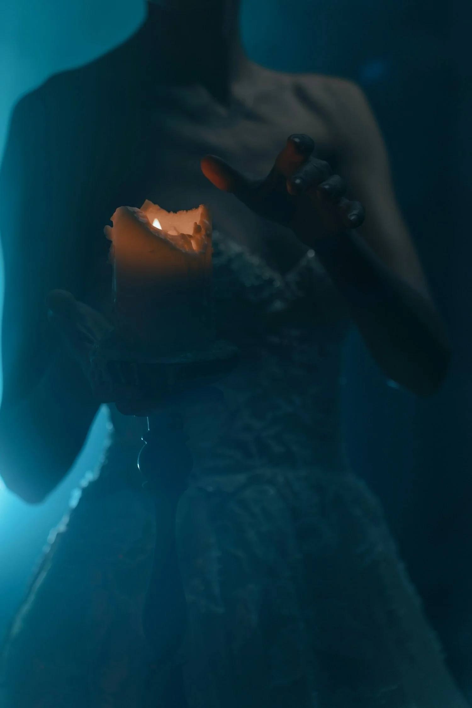 A person holding a lit candle in a dark environment.