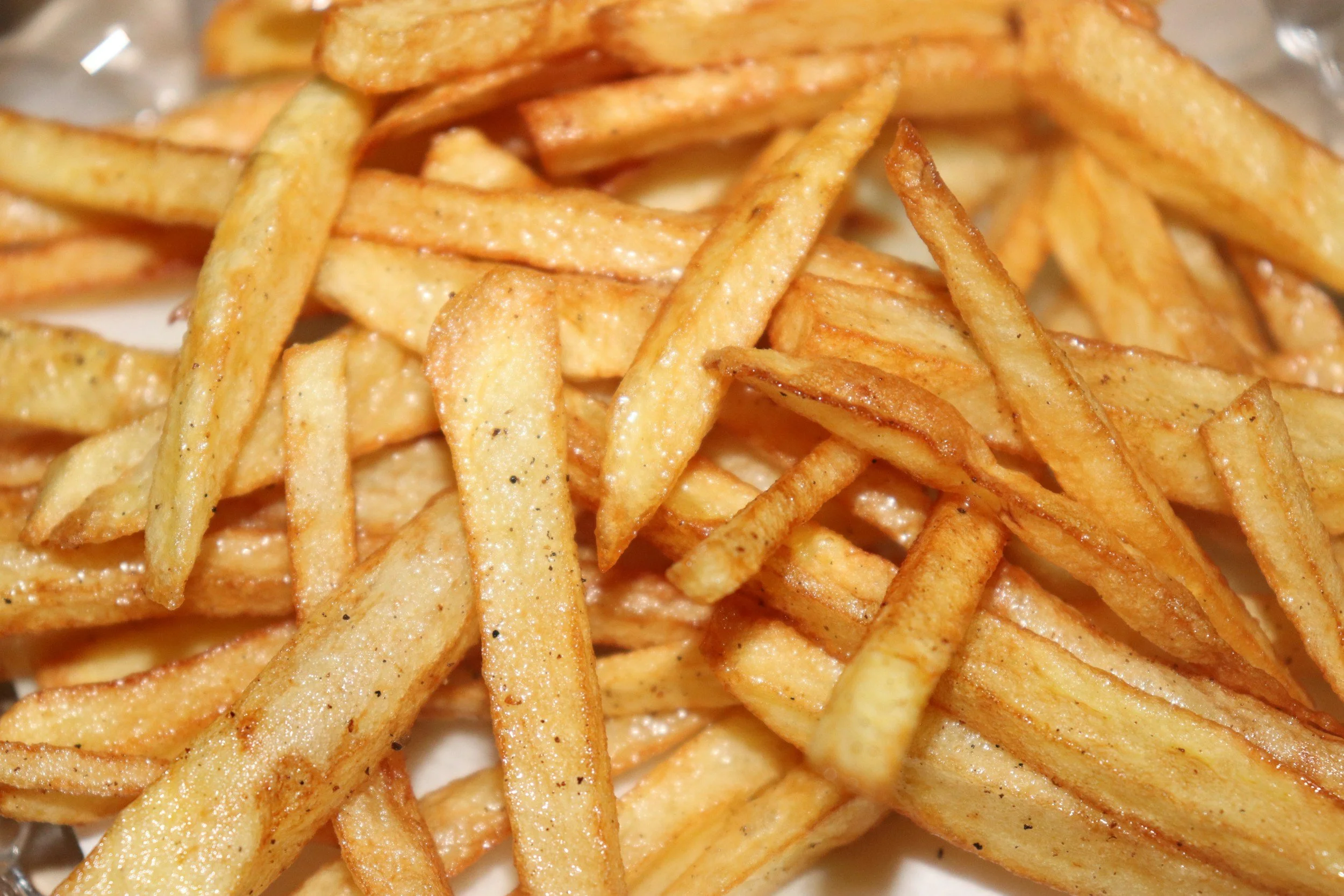 Close-up of crispy French fries seasoned with salt and black pepper.