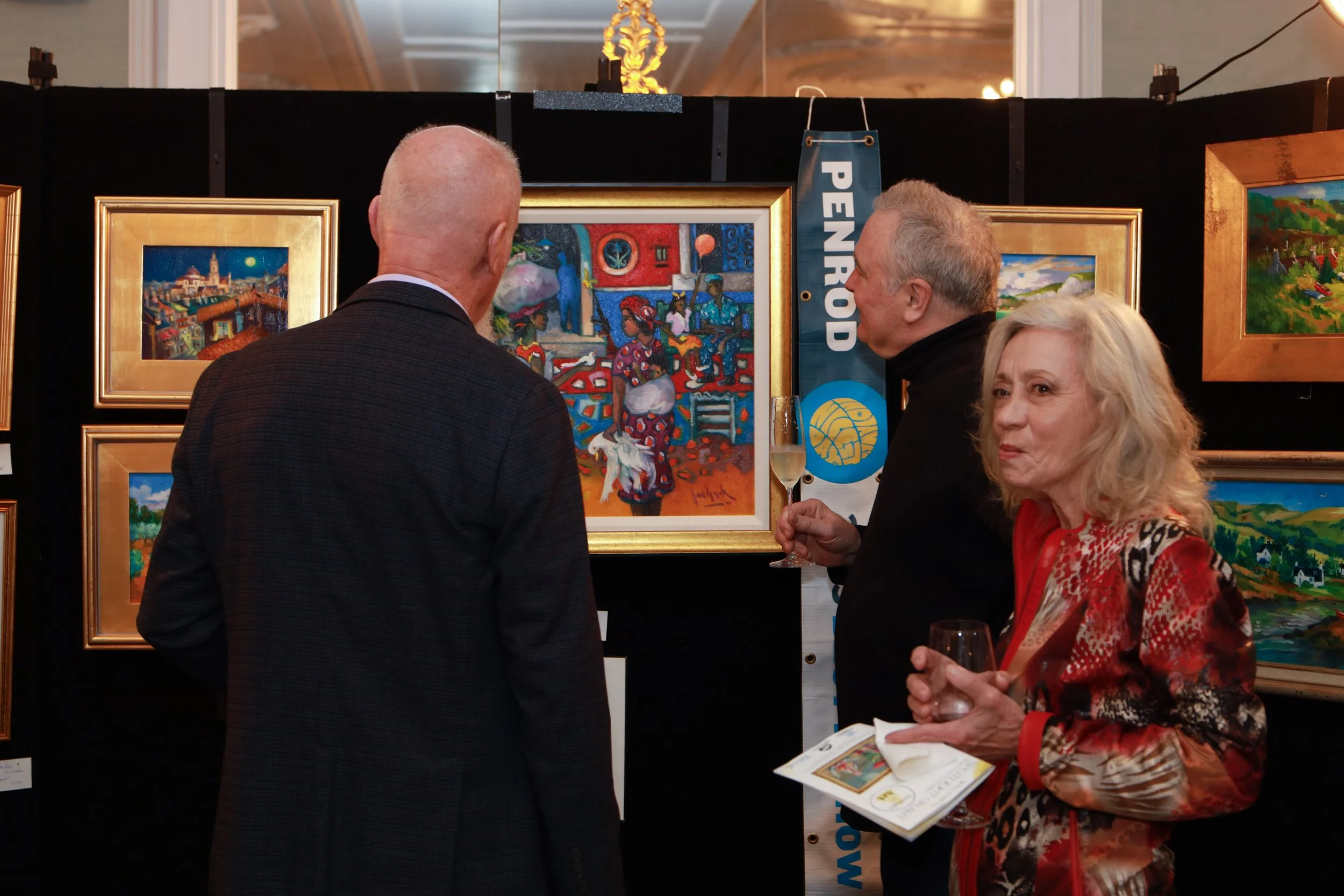 People attending an art exhibition viewing colorful paintings on display.