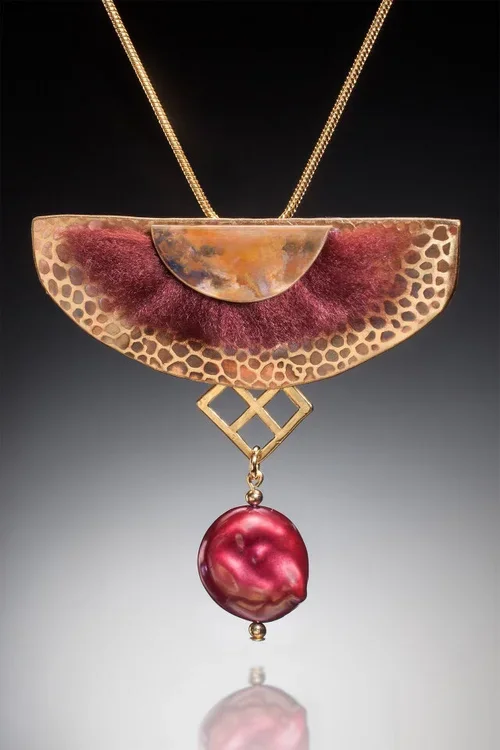 Jewelry necklace featuring a semi-circular gold pendant with honeycomb pattern, purple velvet inlay, and a large irregular pink pearl pendant hanging below.