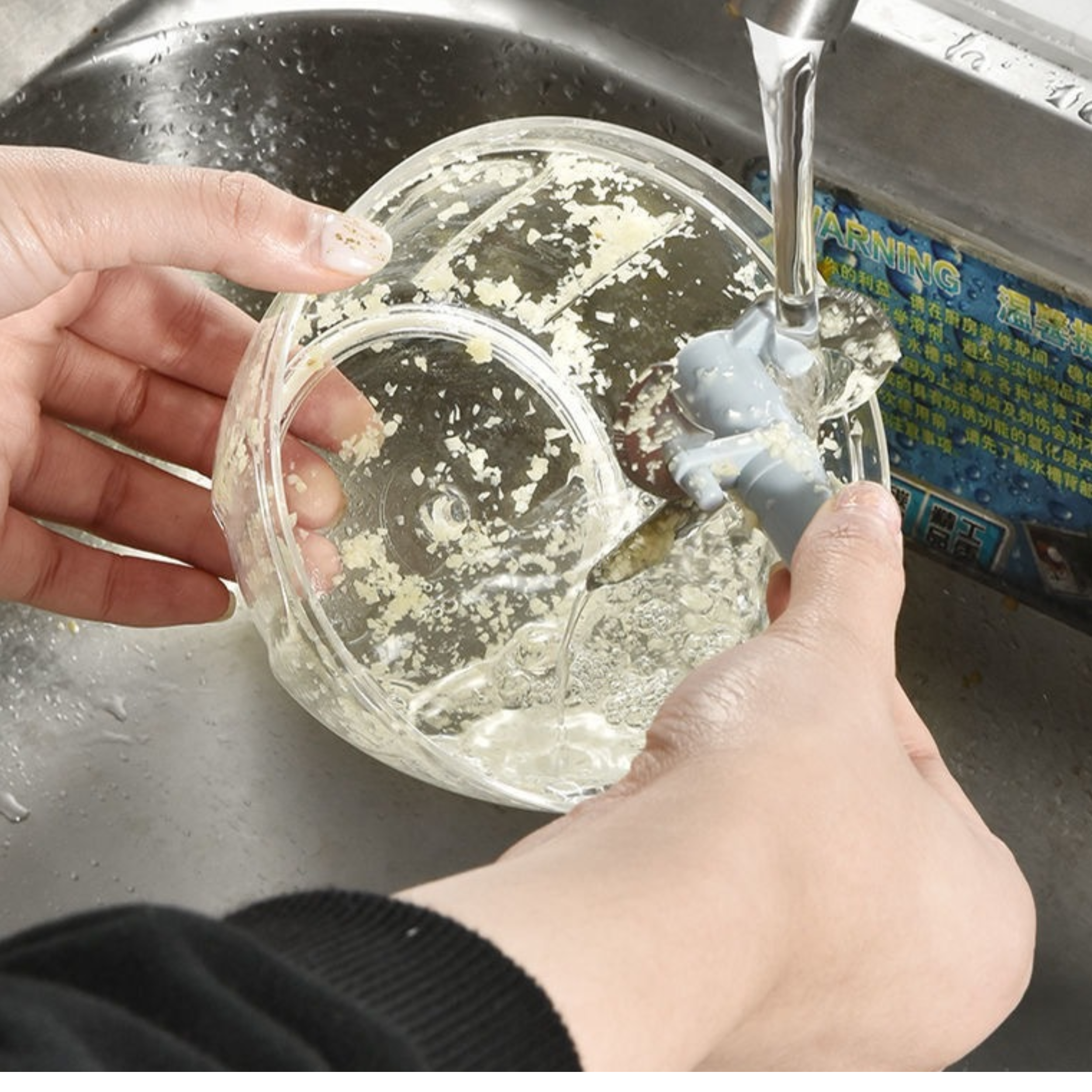 Clear bowl and chopping blade assembly being rinsed under water after using manual food chopper