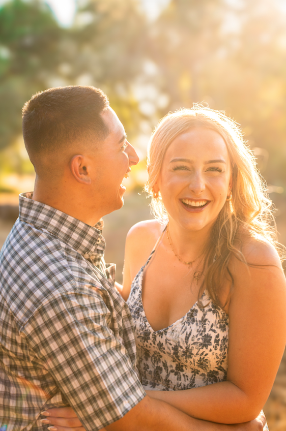 A couple laughing and looking at each other outdoors during sunset during a couples session in Bidwell Park in Chico, CA.