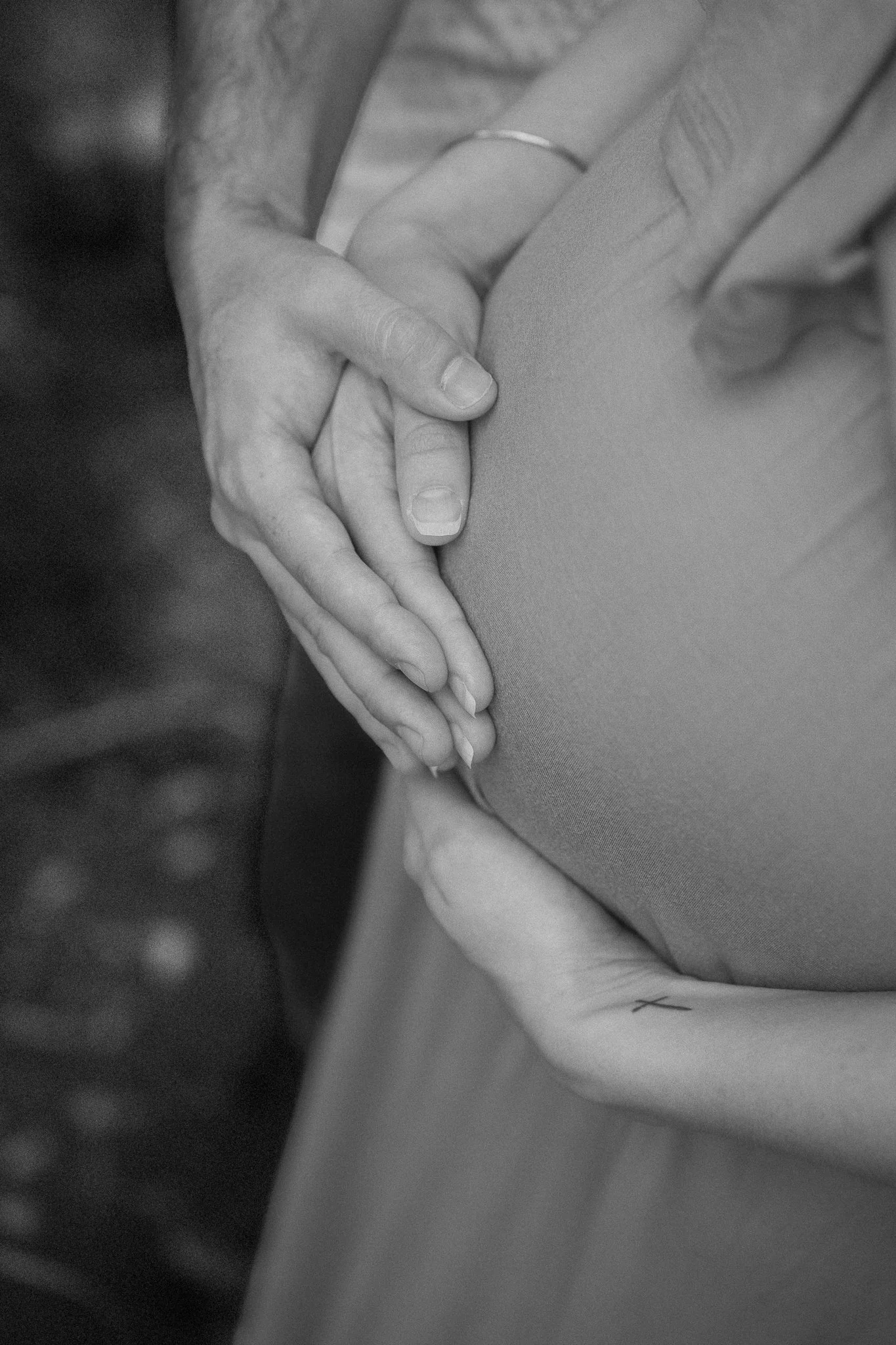 Close-up black-and-white photo of two hands intertwined, with one hand gently resting on the other's wrist.