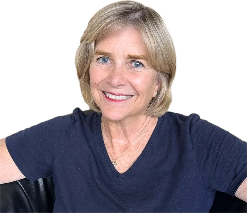 A smiling, welcoming, middle-aged counselor with blonde hair and blue eyes, wearing a navy blue shirt, sitting against a plain background.