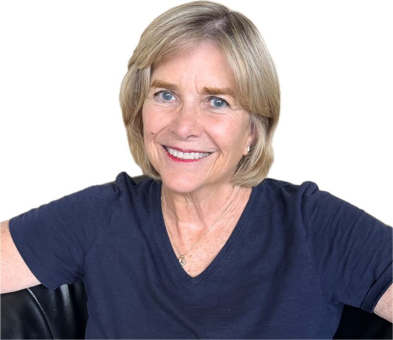 A smiling and welcoming middle-aged therapist with blond hair and blue eyes. Wearing a navy shirt and sitting in a black chair.