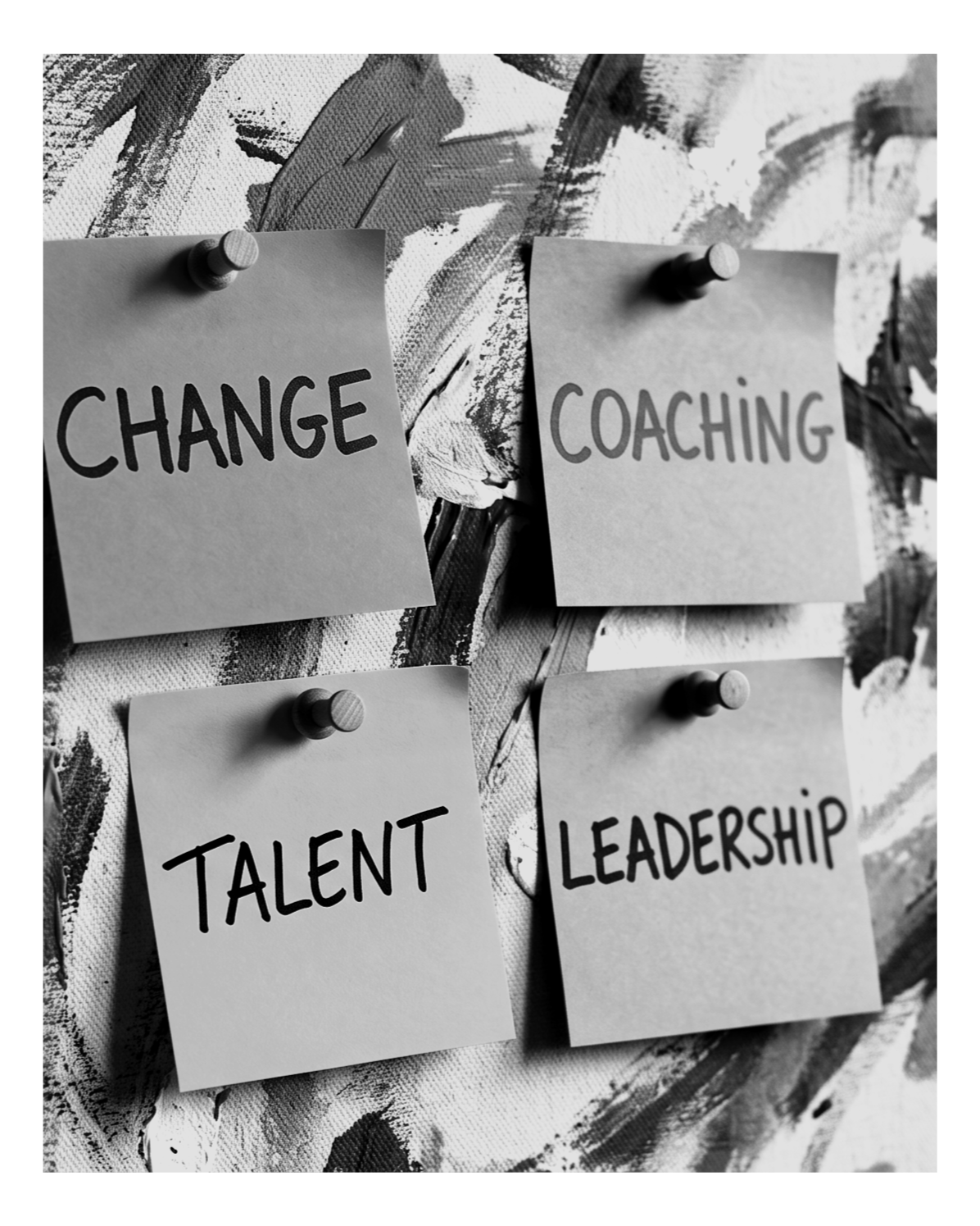 Four notes pinned to a board with words 'Change,' 'Coaching,' 'Talent,' and 'Leadership' written on them.