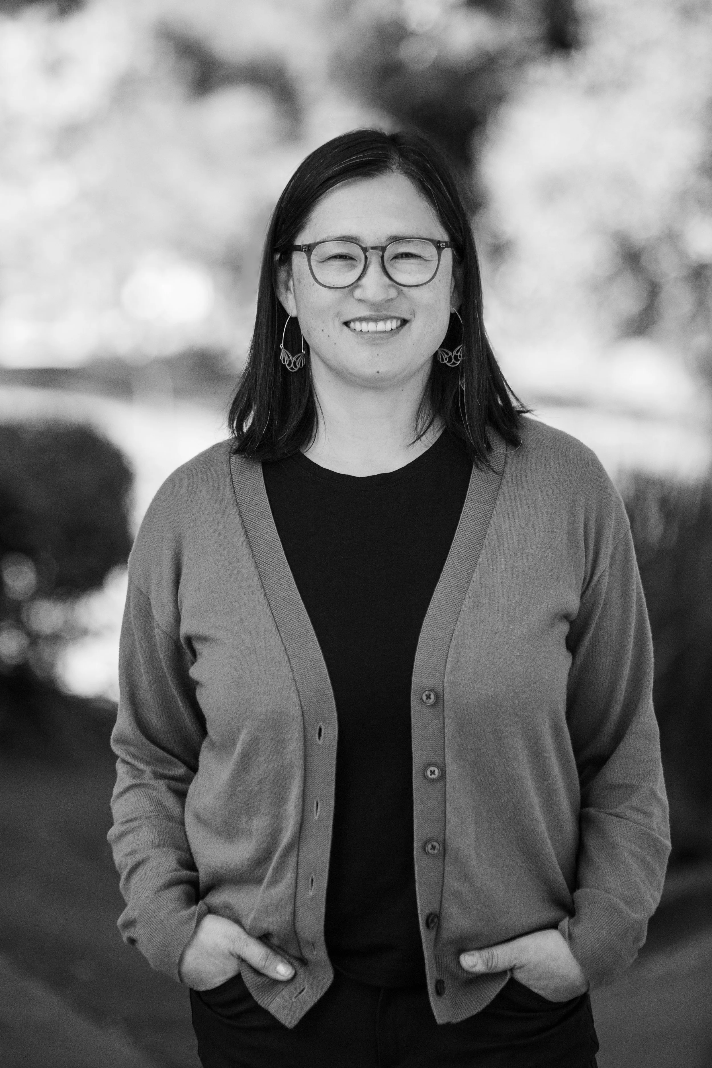 A black and white photograph of Sandy Park, candidate for Berkeley School Board 2026, smiling and wearing glasses and a cardigan.