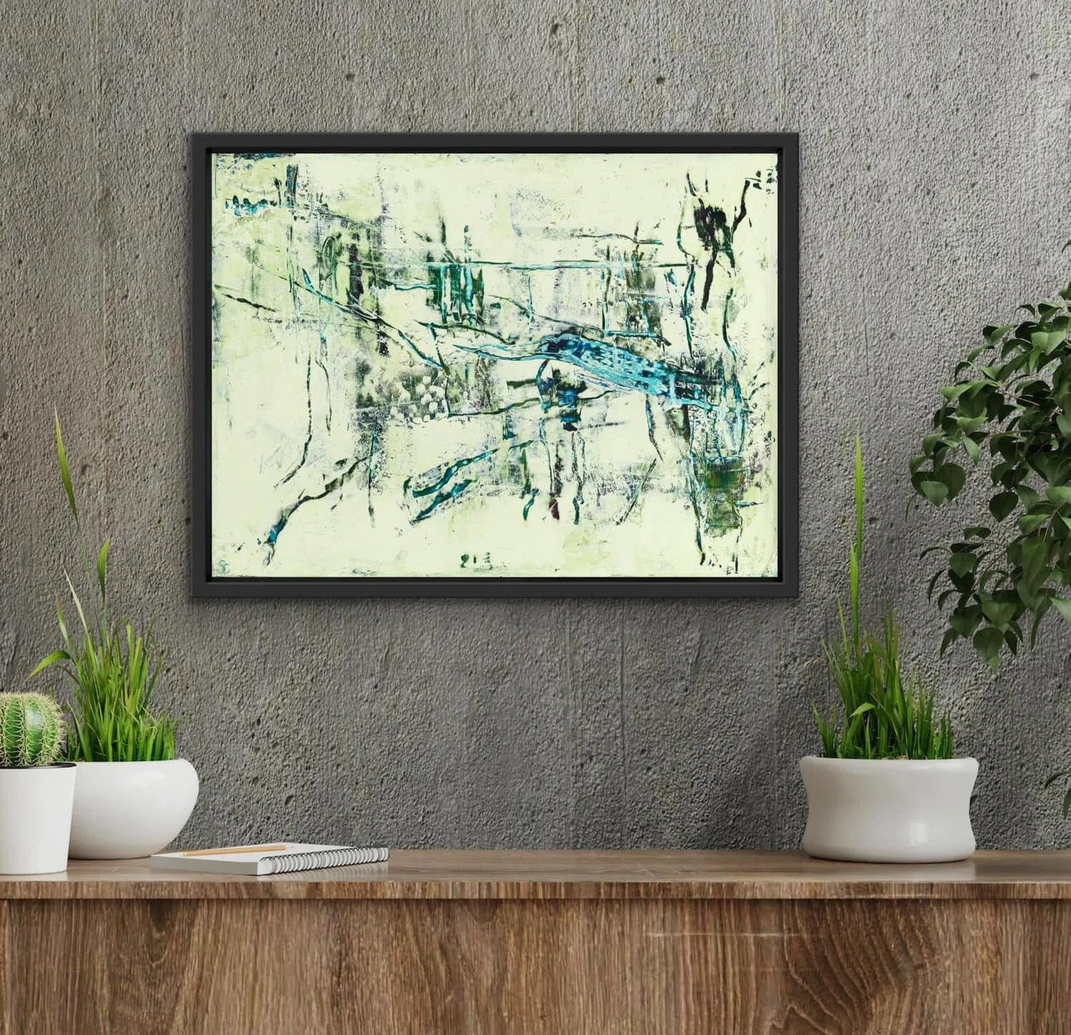 Abstract painting with blue, green, and black brushstrokes hanging on a beige textured wall, flanked by potted green plants on a wooden surface.